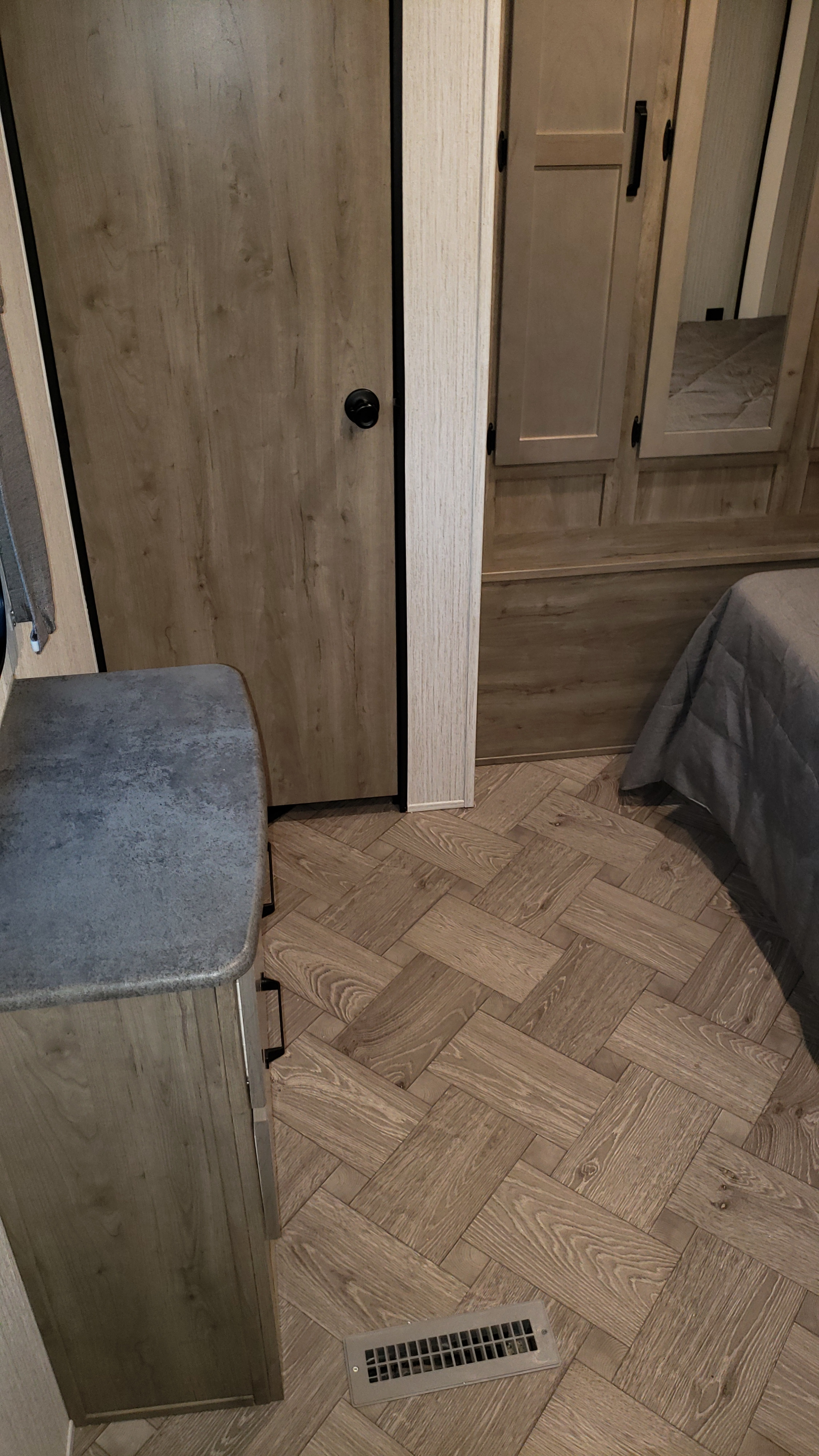 Inside an RV rental: detailed view of herringbone wood flooring, light wood cabinets, and a bed area. Practical and stylish RV living.. Palomino 32BHQS 2022