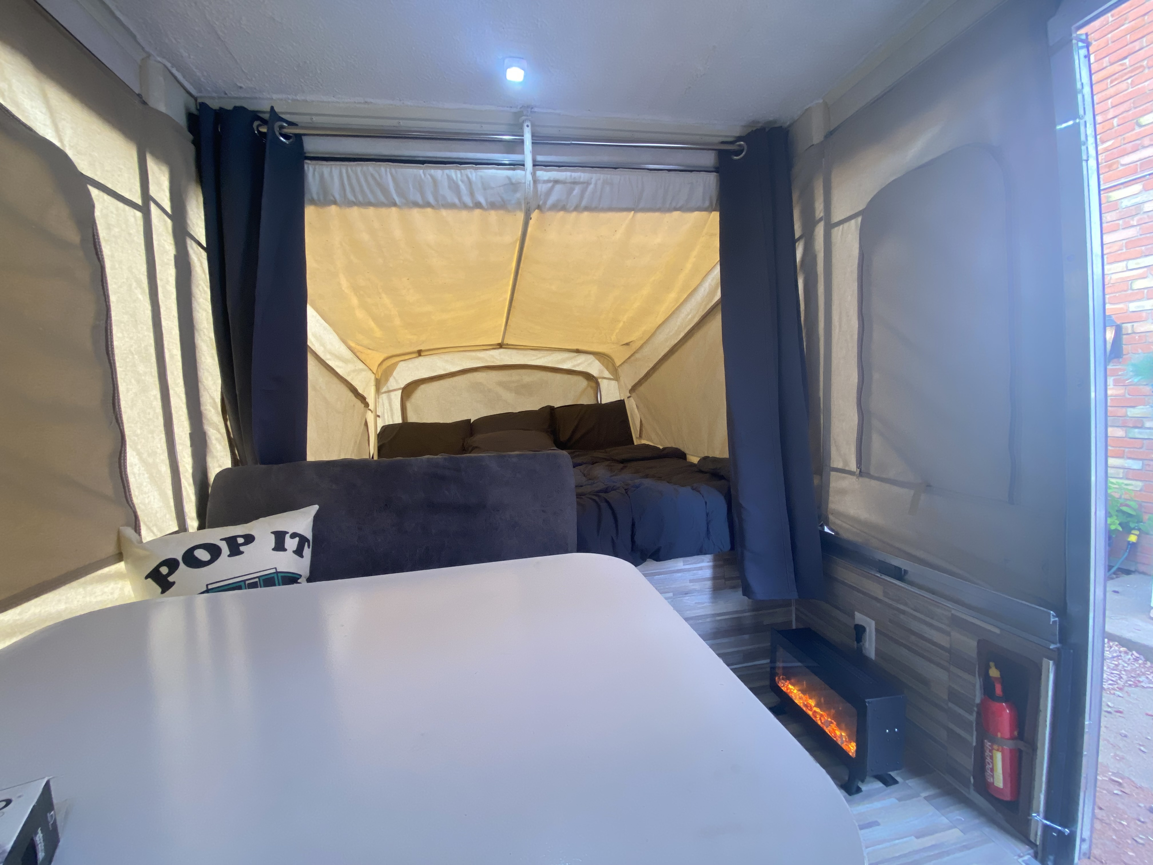 Inside a comfy RV rental: a pop-up camper boasts a bed, dining, seating, and a glowing fireplace.. Coleman Fleetwood 1991
