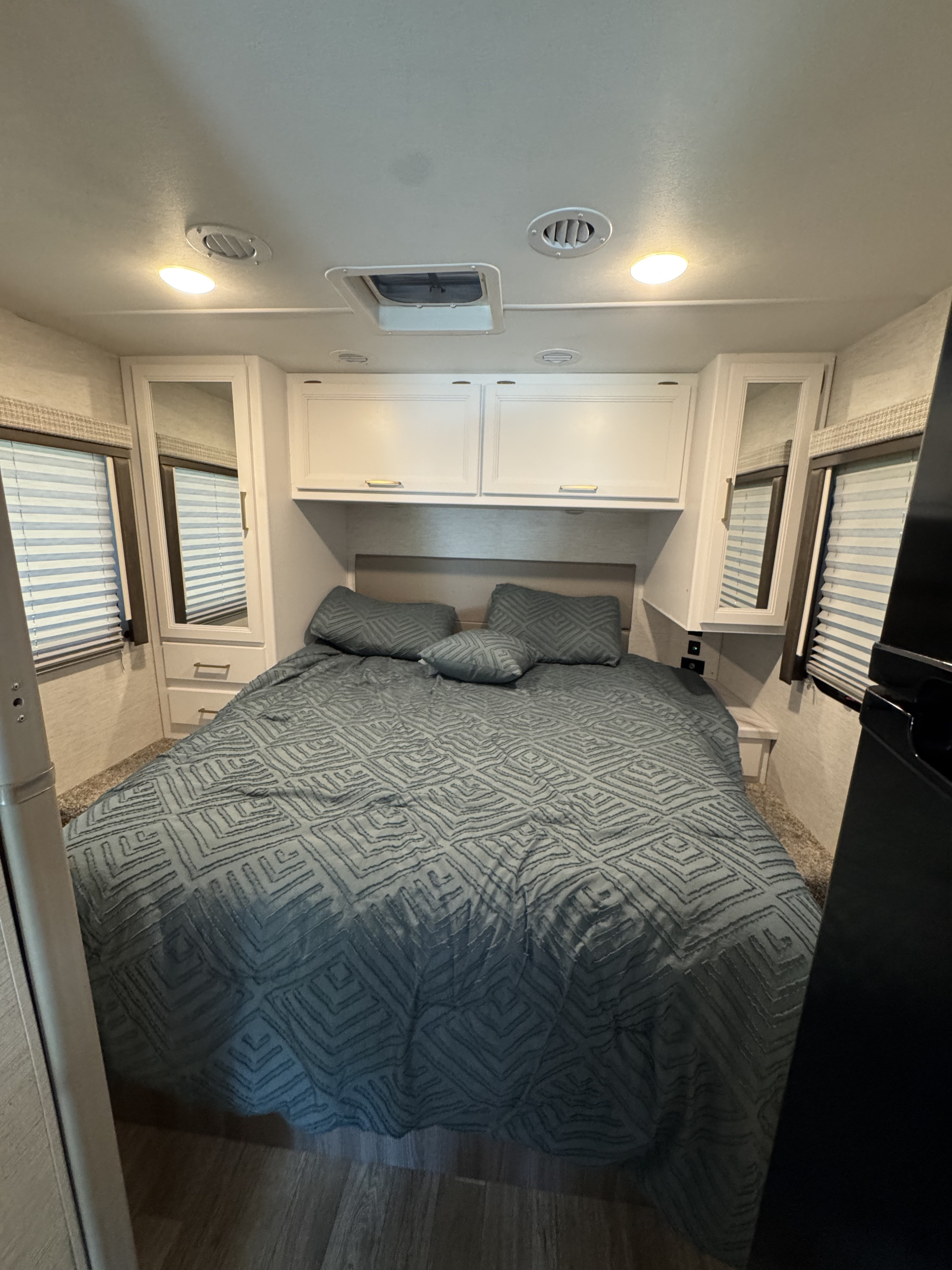Cozy RV rental bedroom with a comfortable bed, overhead cabinets, and windows. Perfect for travel.. Thor Eddie Bauer 28EB 2025