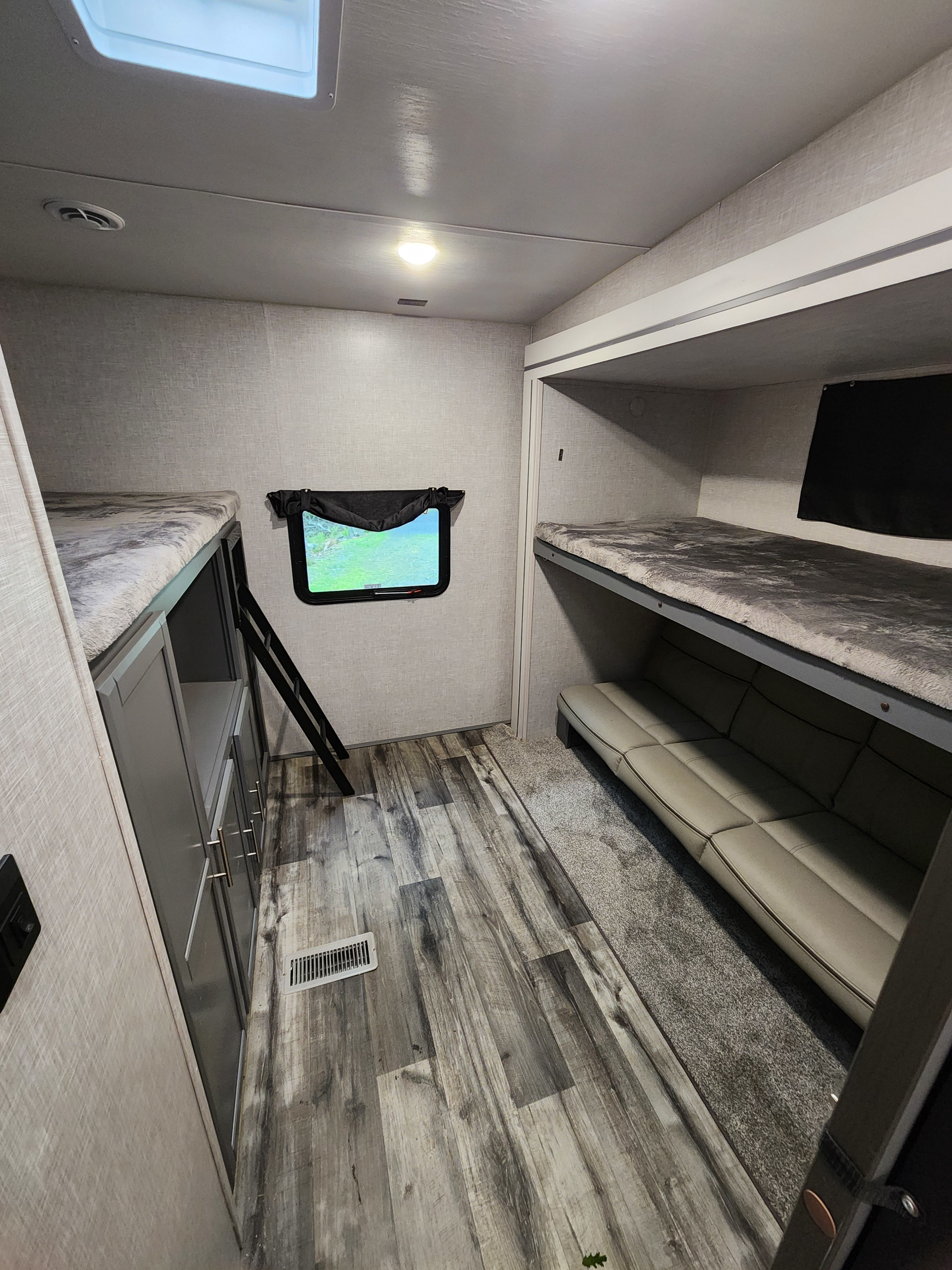This RV rental interior features comfortable bunk beds, a cozy sofa, and durable flooring for family adventures.. Crossroads RV Volante 2022