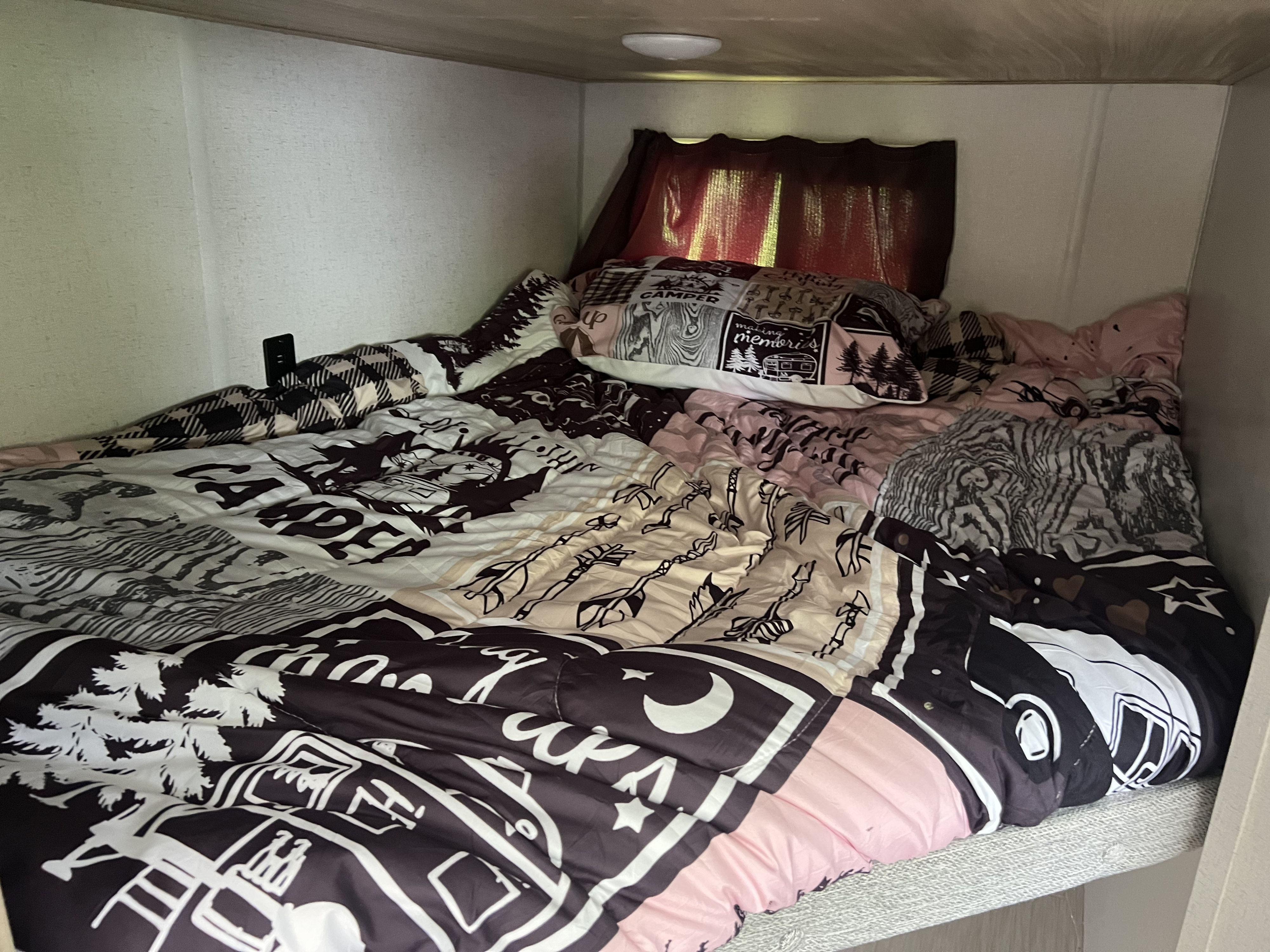 Cozy bunk bed inside an RV rental, featuring a unique patterned comforter with camping and nature designs.. Forest River Salem FSX 2023