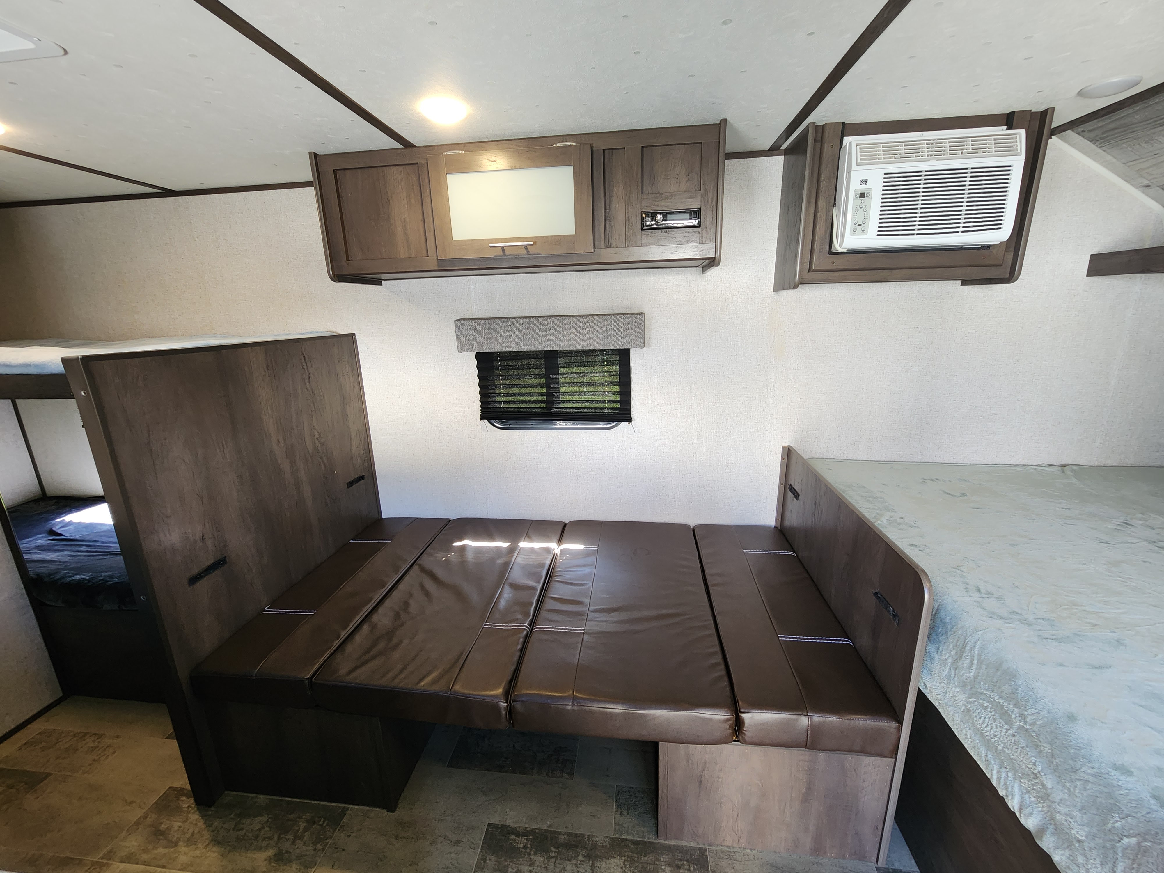 RV rental interior featuring a convertible dinette bed, bunk beds, overhead cabinets, and an AC unit.. Dutchmen Coleman Lantern LT 2021