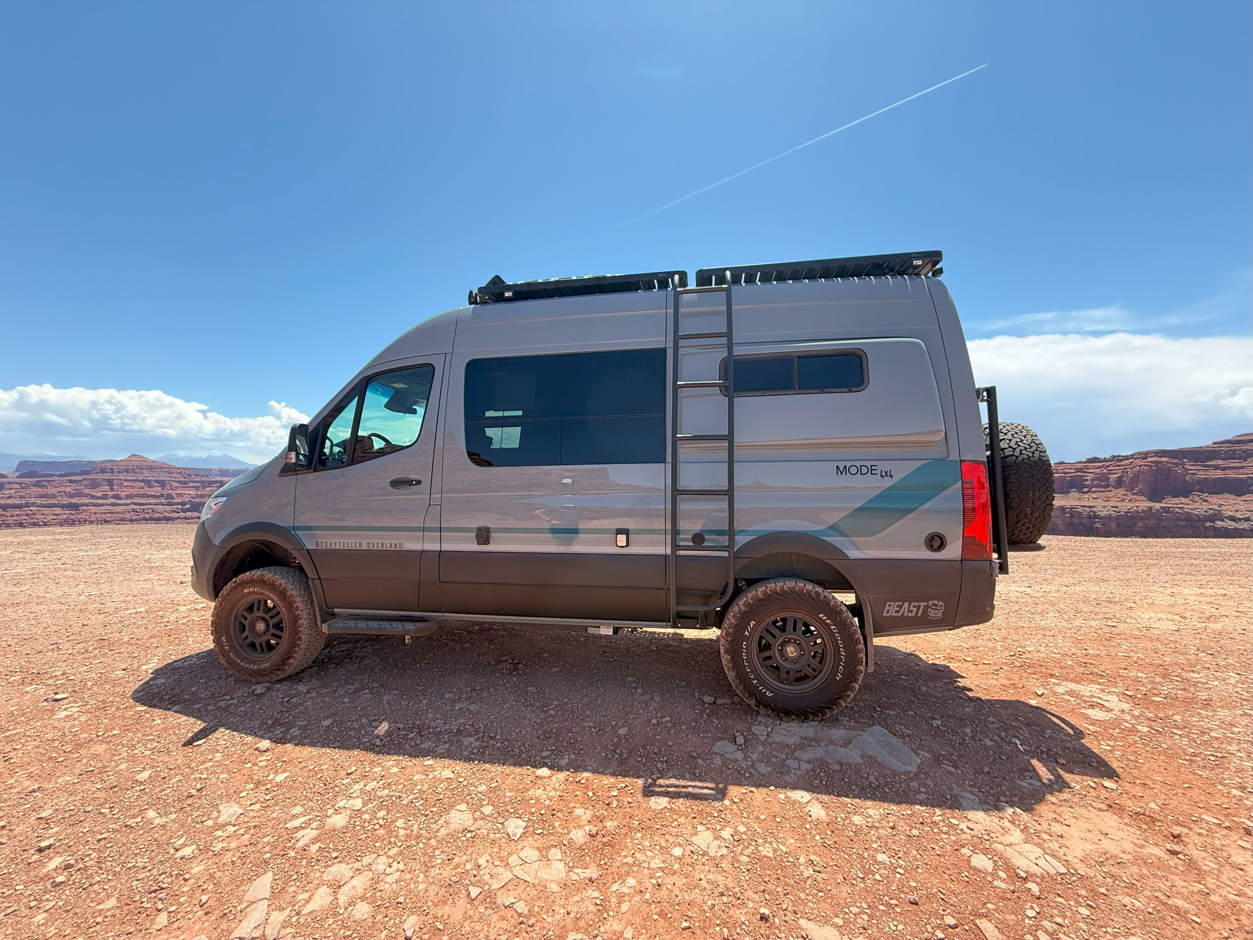 Gray Storyteller Overland camper van for rv rental, parked on red earth with distant desert mountains, ideal for adventure travel.. Storyteller Overland Storyteller Overland Class B 2023