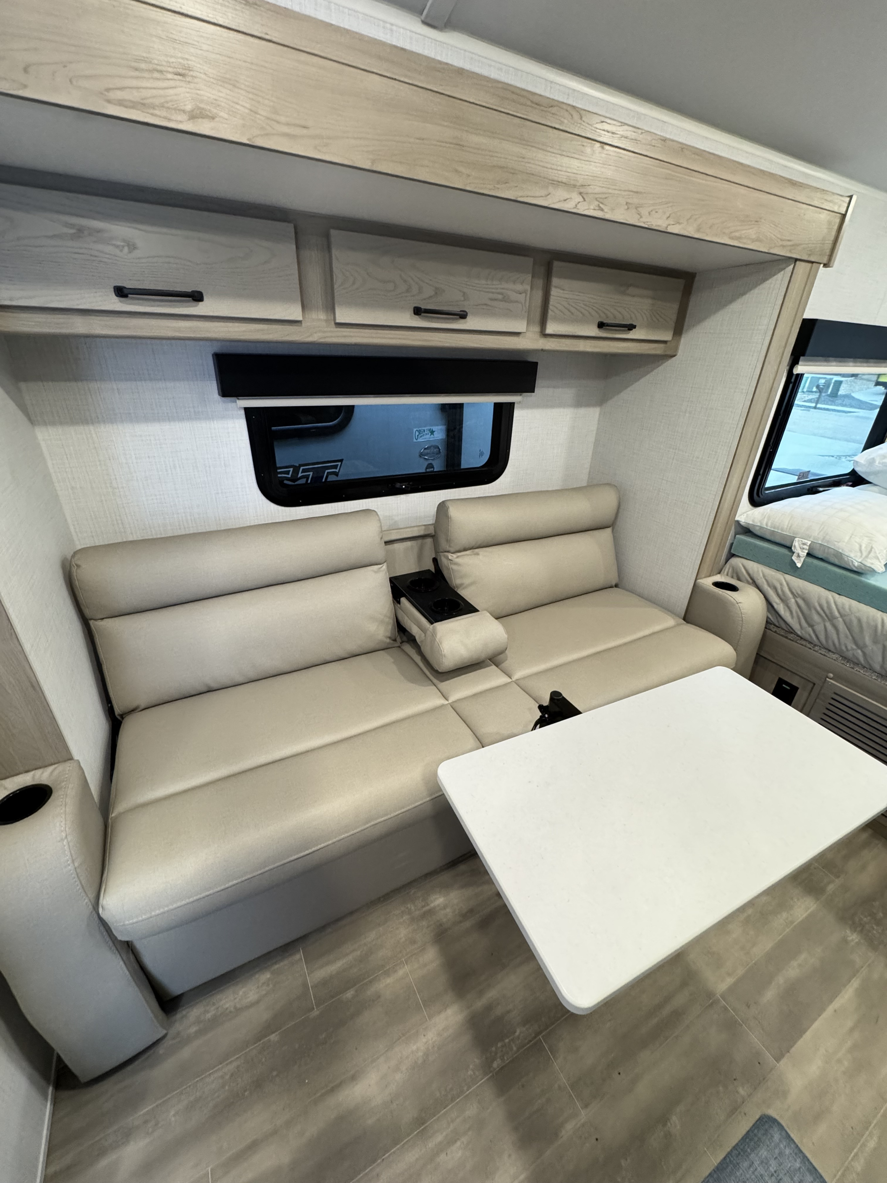 RV rental interior: comfy light sofa seating with cupholders, a table, and overhead cabinets.. Forest River Rockwood Geo Pro 2024