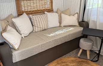 Comfortable RV rental interior showcasing a plush daybed with pillows and a small side table, perfect for relaxing.. Forest River Rockwood Geo Pro 2019