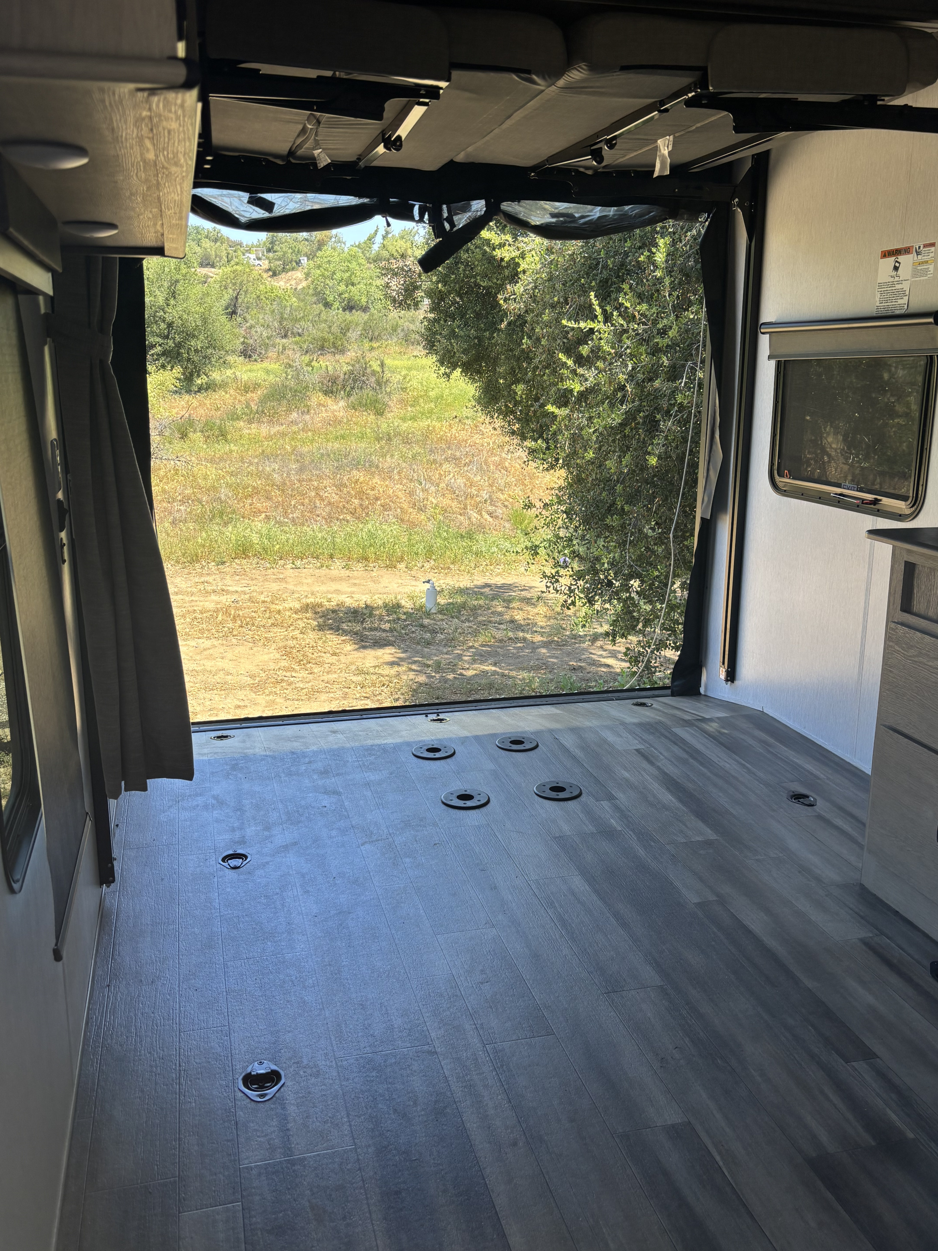 RV rental toy hauler: rear cargo area opened to nature, revealing flexible floor space with tie-downs & overhead bunk beds.. Forest River Stealth 2024
