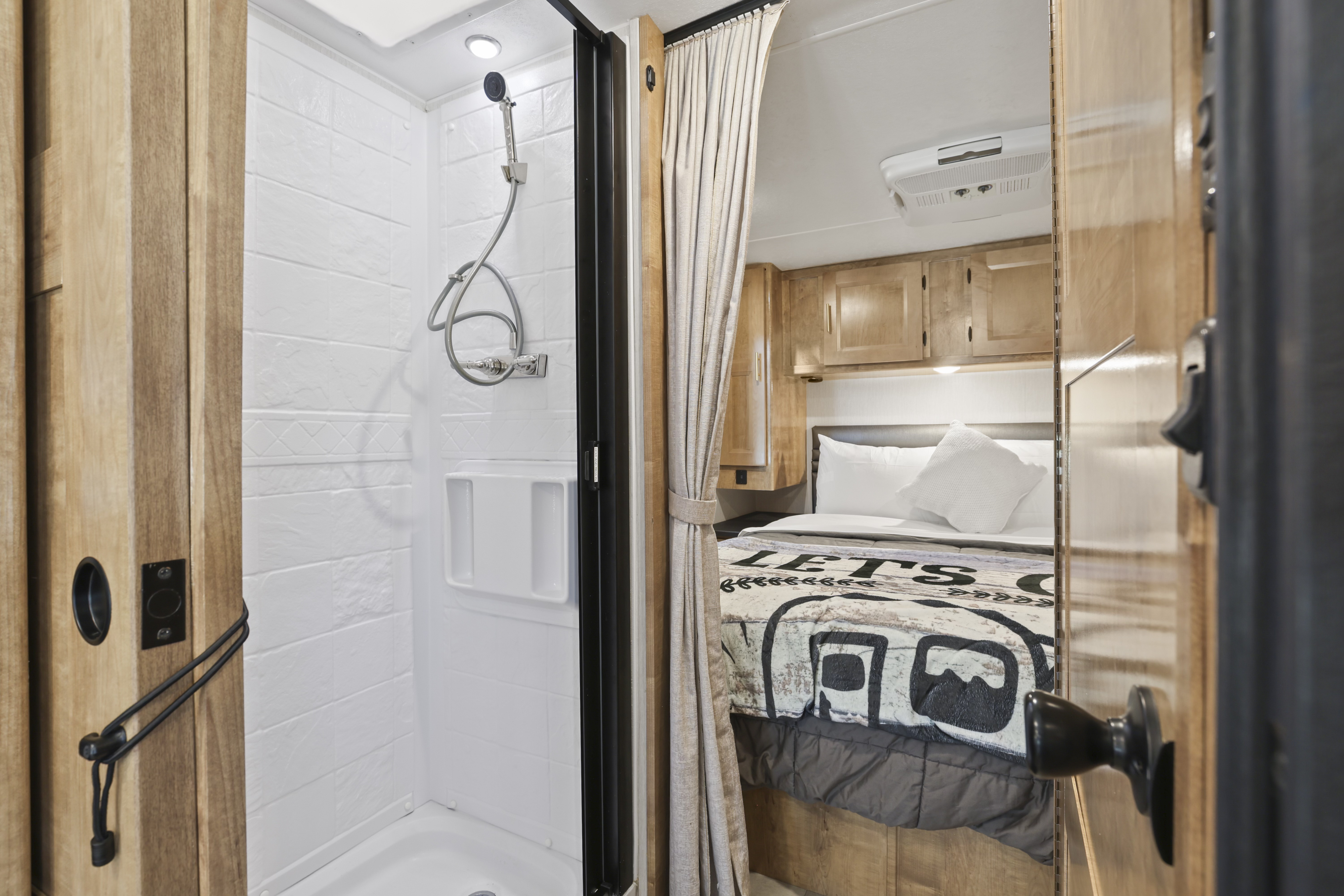 Cozy RV rental interior showcasing a compact shower and a comfortable bedroom with overhead cabinets.. Forest River Coachmen Leprechaun Premier 2021