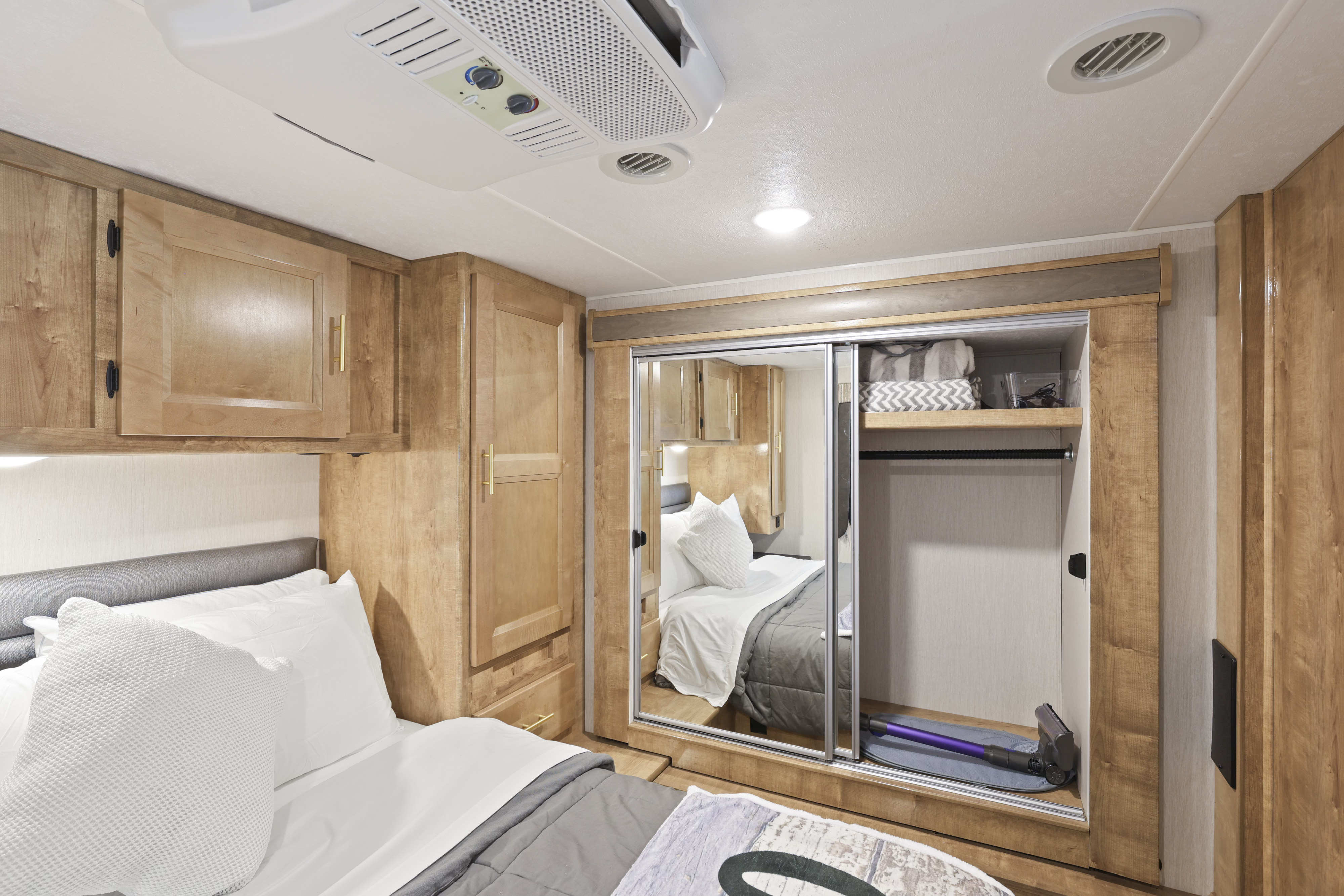 Cozy RV rental bedroom with mirrored closet, comfortable bed, and ample storage, perfect for your next adventure.. Forest River Coachmen Leprechaun Premier 2021