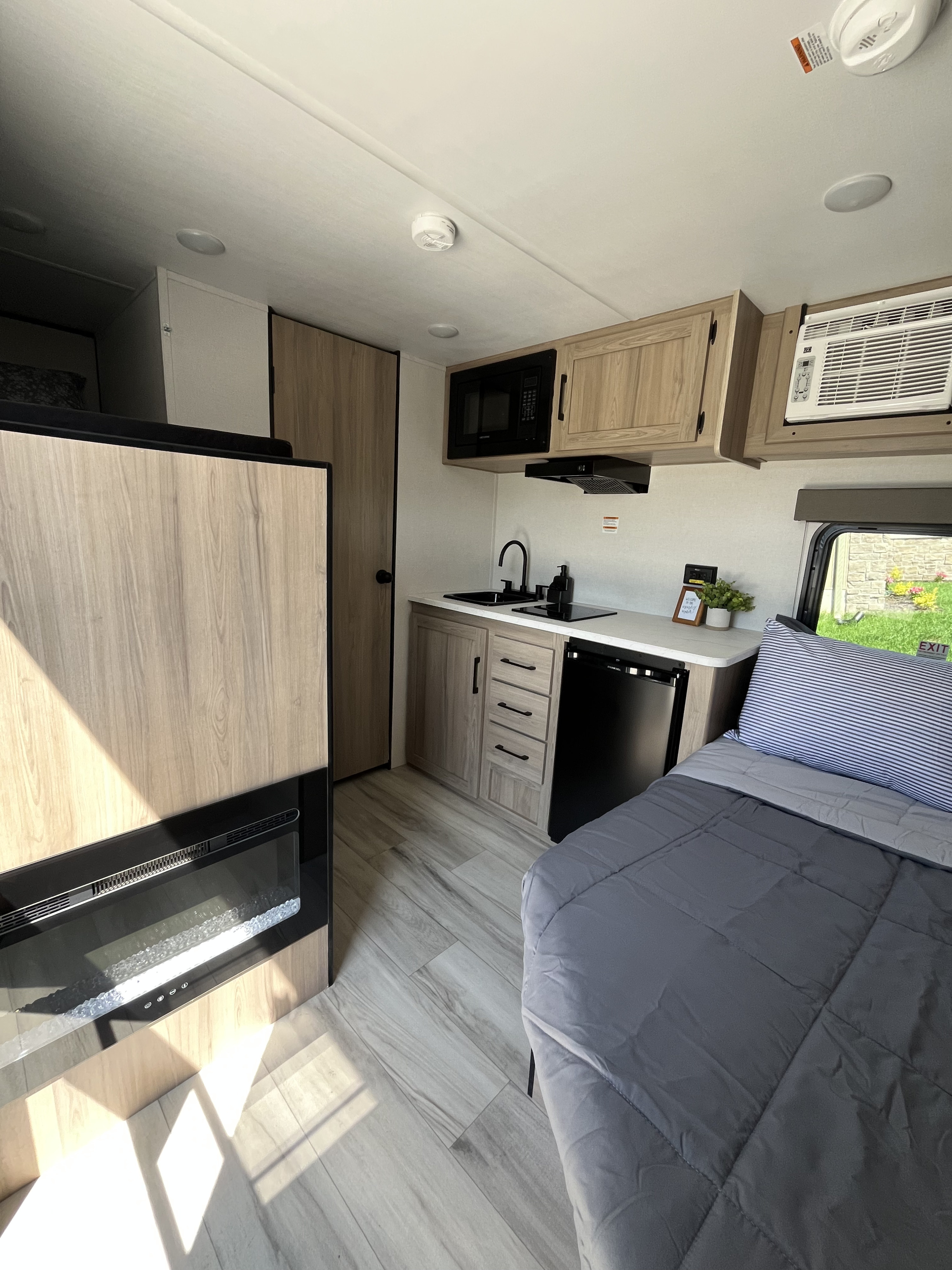 Step into this RV rental, featuring a compact kitchen, comfortable bed, and cozy electric fireplace for your travels.. Keystone Bunkhouse 2025
