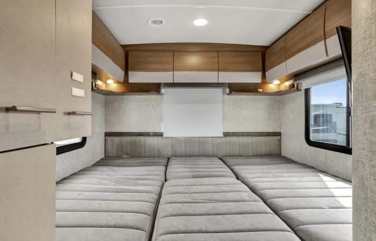 Spacious RV rental interior with a comfortable, segmented bed, overhead storage, and TV, perfect for your next road trip.. Winnebago View 2017