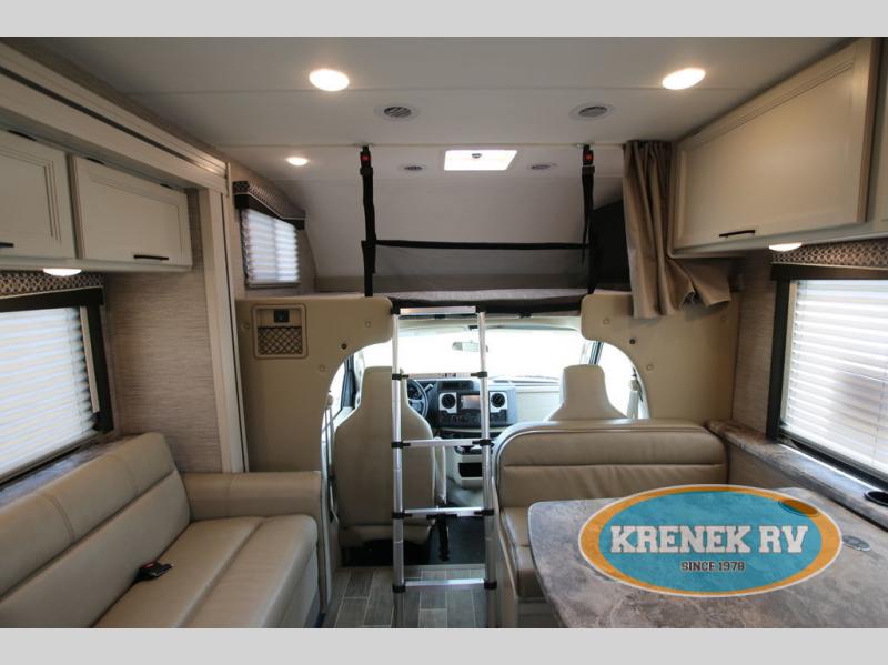 Spacious RV rental interior featuring a sofa, dining table, and bunk bed above the driver's cab.. Thor Chateau 2022
