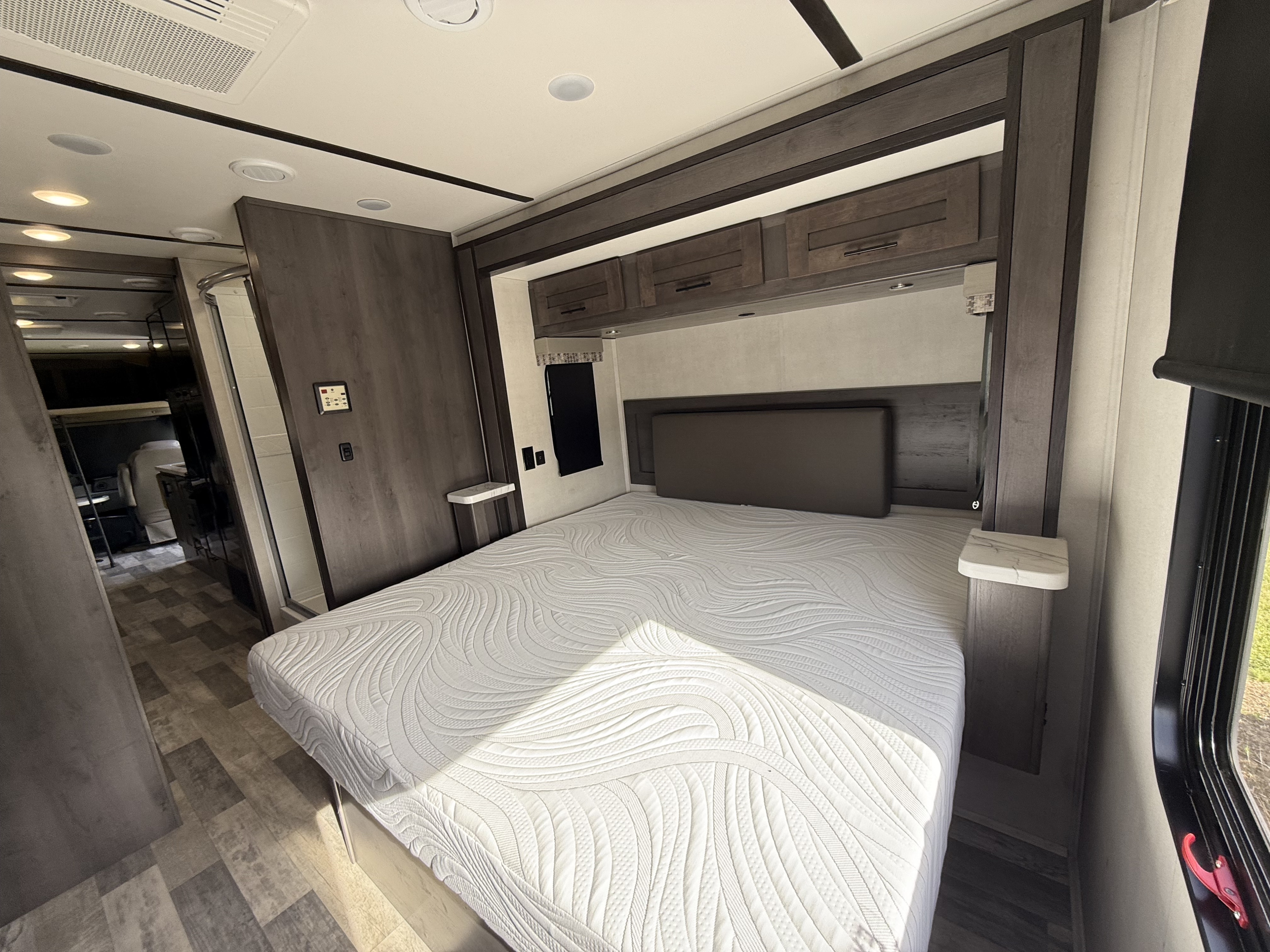 Clean RV rental shower with curved glass door, black fixtures, and skylight. Ready for refreshing stops on your journey.. FR3 FR3 Motorhome 2023