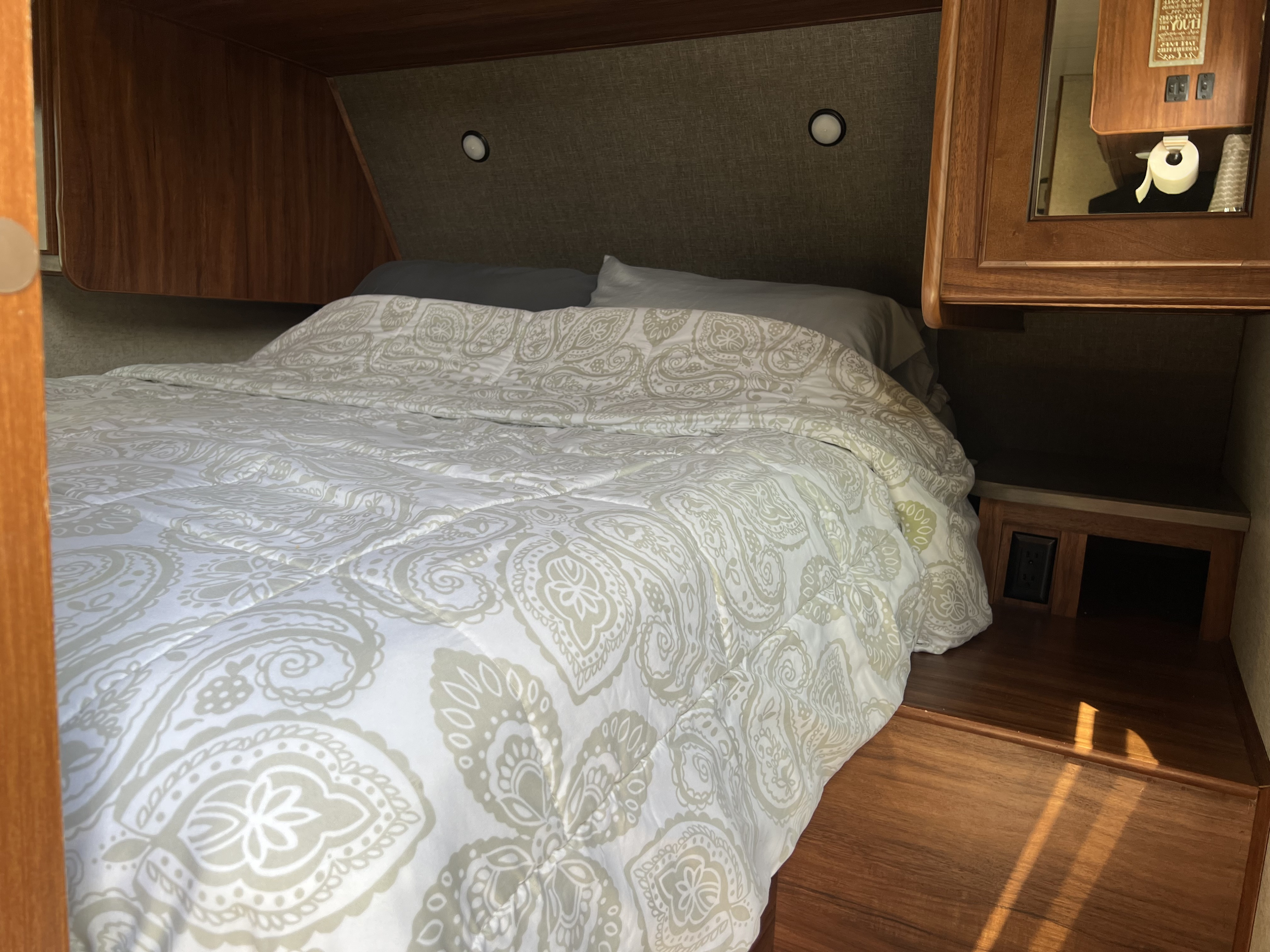 Cozy RV rental bedroom with a comfy bed, white/sage green paisley comforter, and wood cabinets. Perfect for your next adventure!. Heartland RVs Mallard 2018