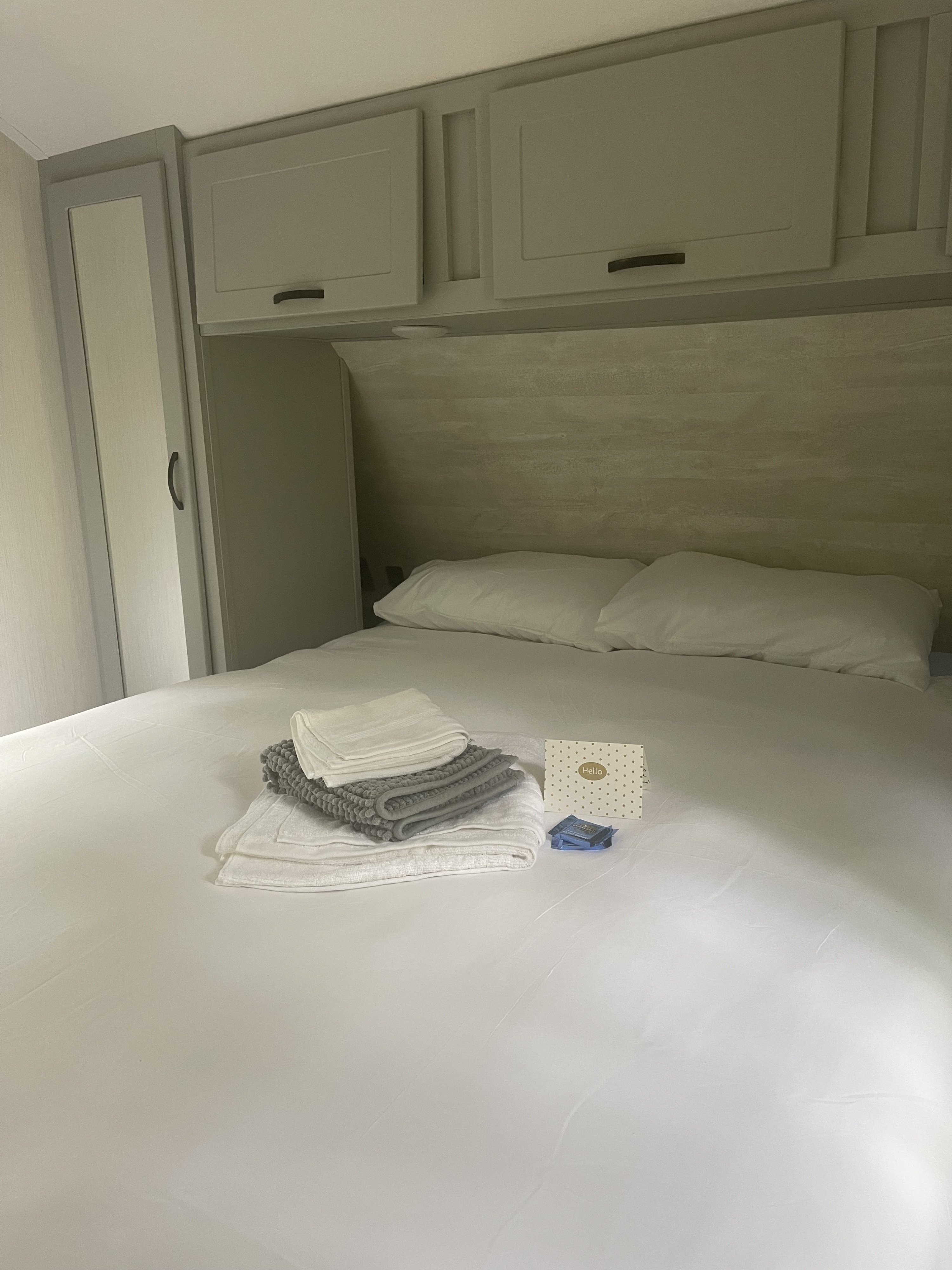 Inside an RV rental: a neat bedroom featuring a comfortable white bed, clean towels, and practical overhead storage.. Forest River Vibe 2022