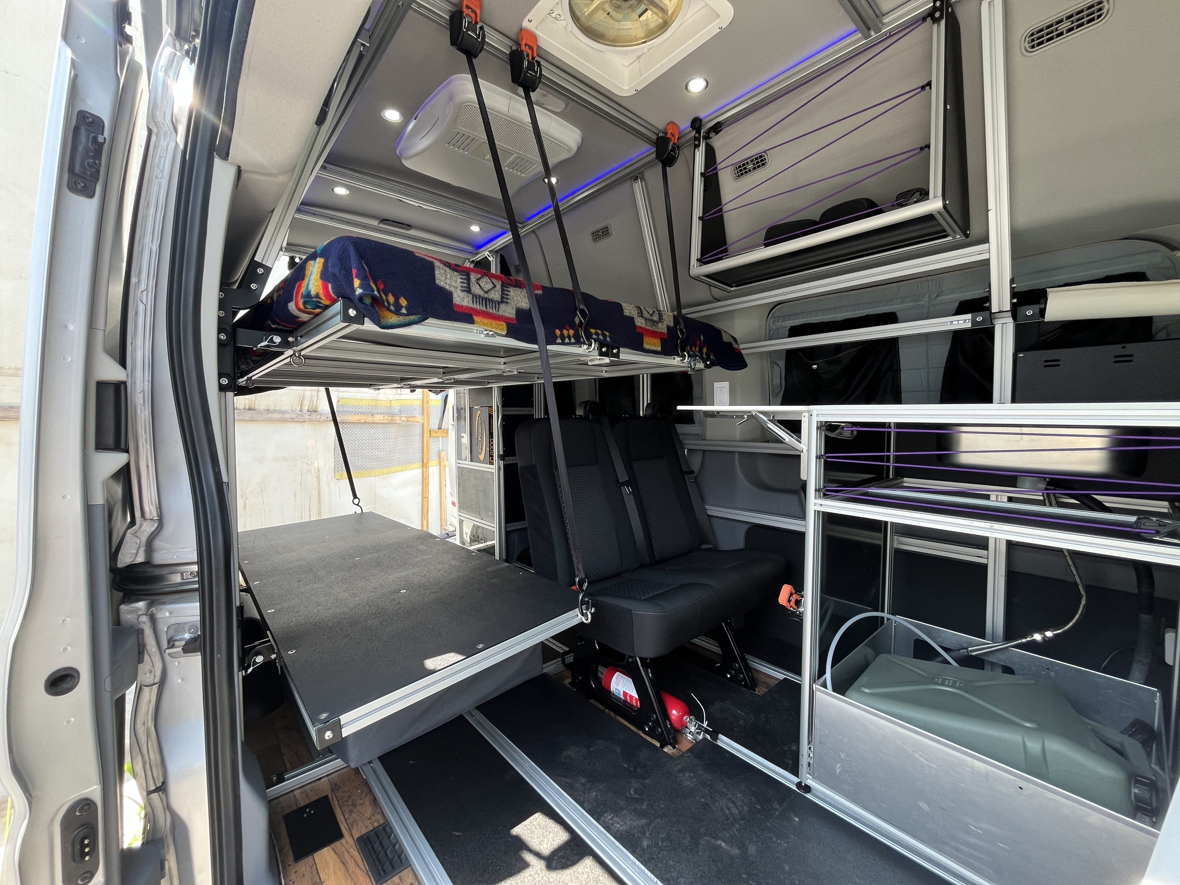 This modular RV rental interior features an elevated bed, seating, and organized storage for adventure.. Vandoit DO 2019