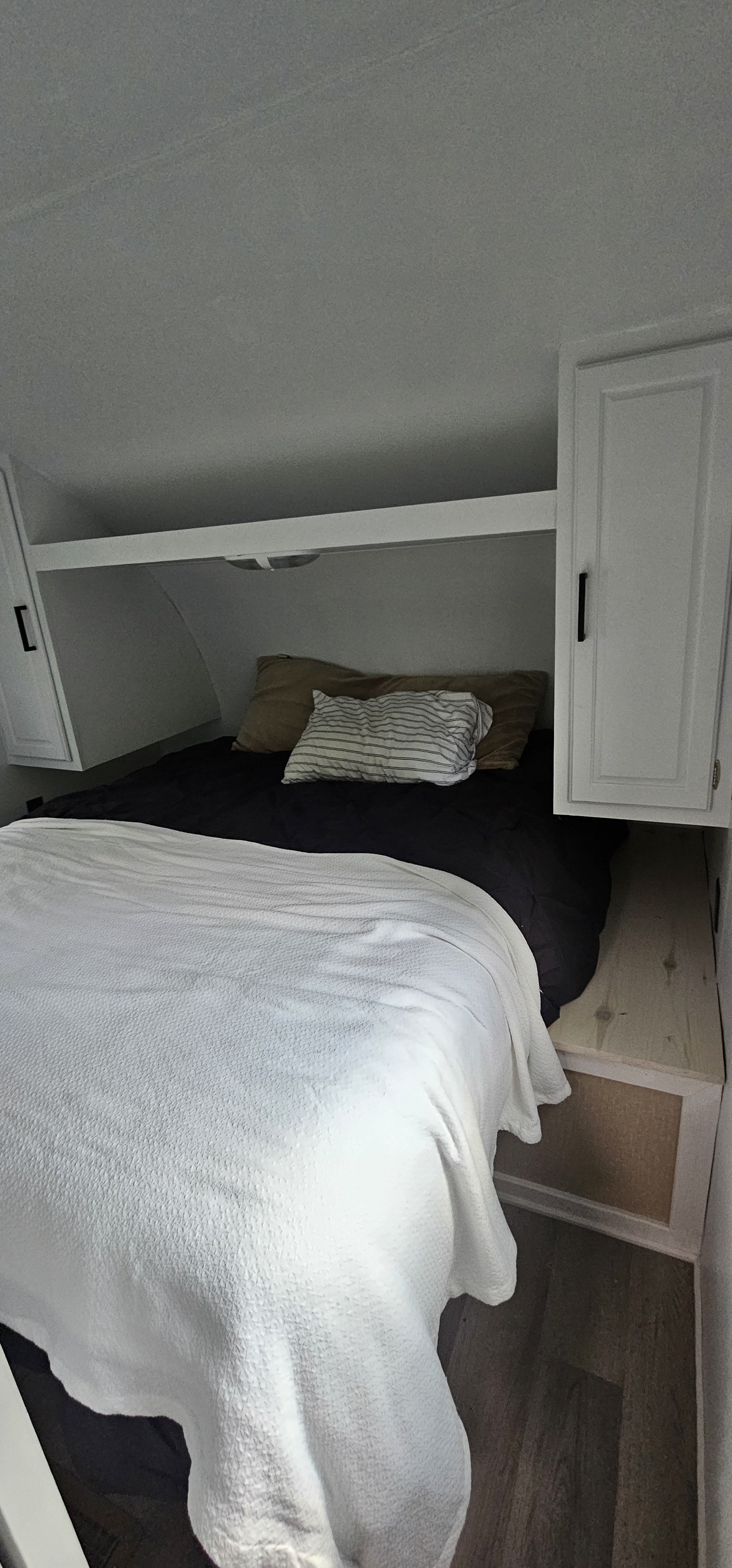 RV rental bedroom view: a neatly made bed with white and black bedding, flanked by white overhead cabinets and storage.. Crossroads RV Z-1 2015
