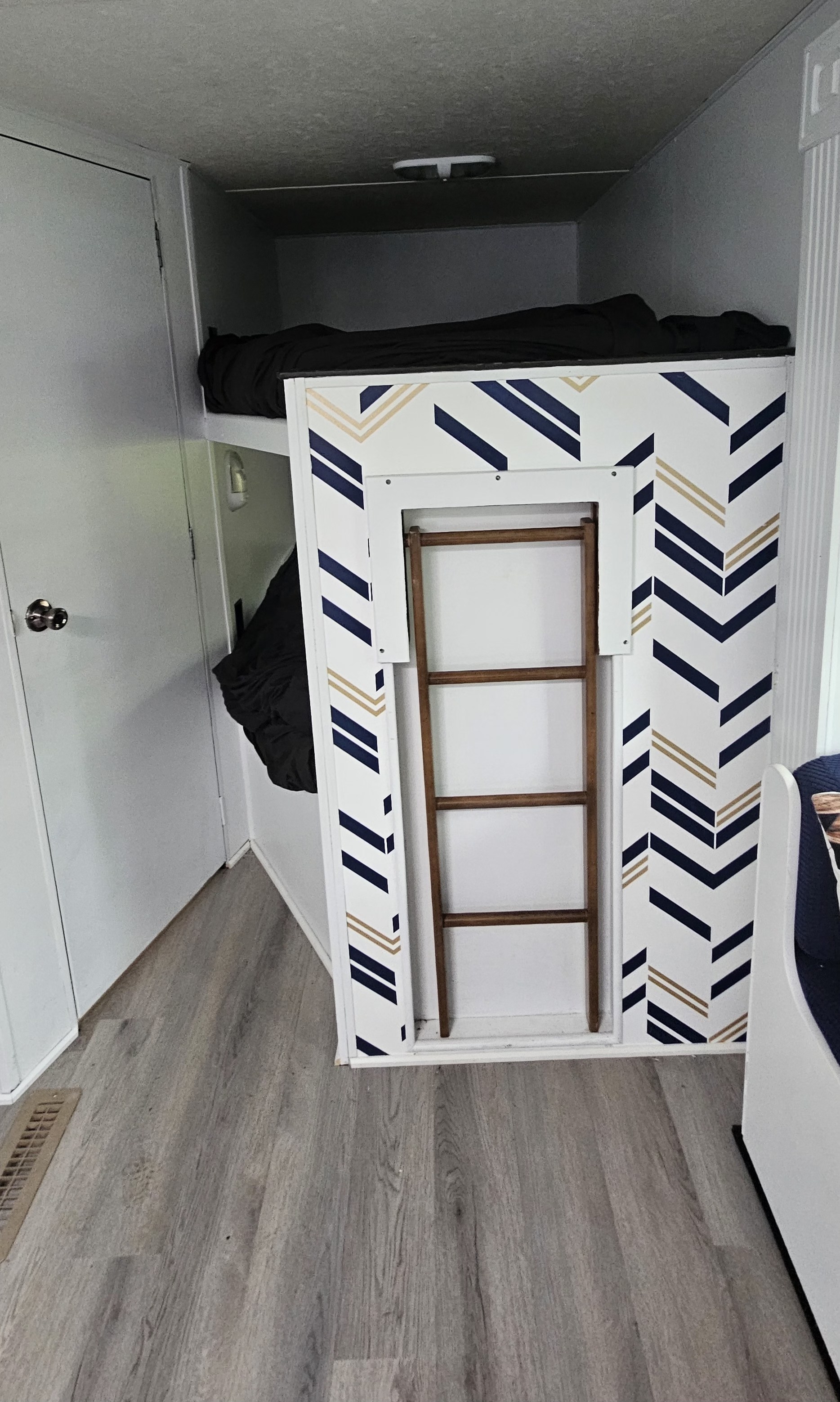 Space-saving RV rental bunk bed area with integrated ladder and modern chevron patterns, ideal for compact living.. Crossroads RV Z-1 2015