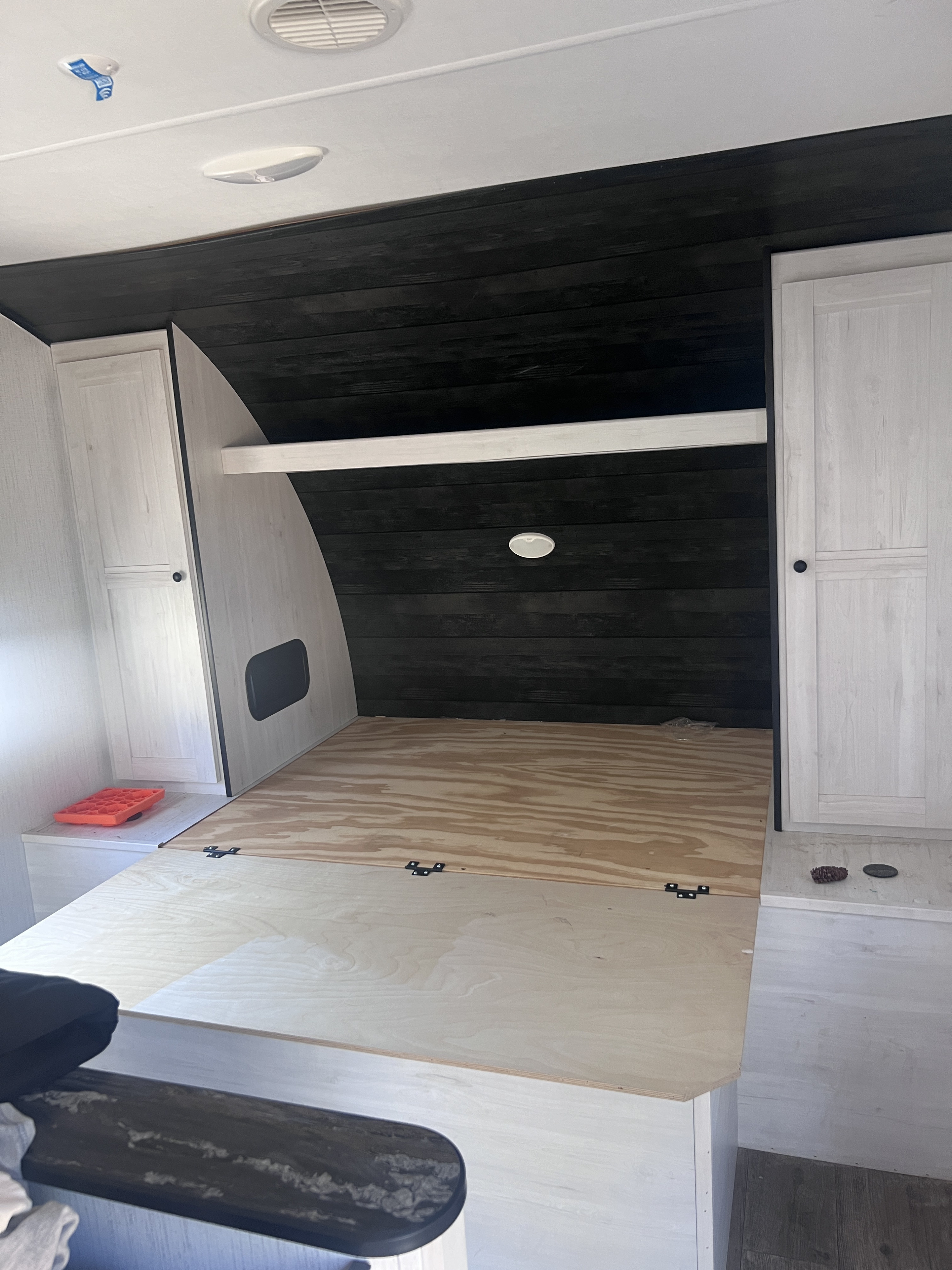 RV rental bedroom: a newly renovated space with dark wood paneling, light cabinets, and a fresh plywood bed.. Heartland RVs Trail Runner 2021