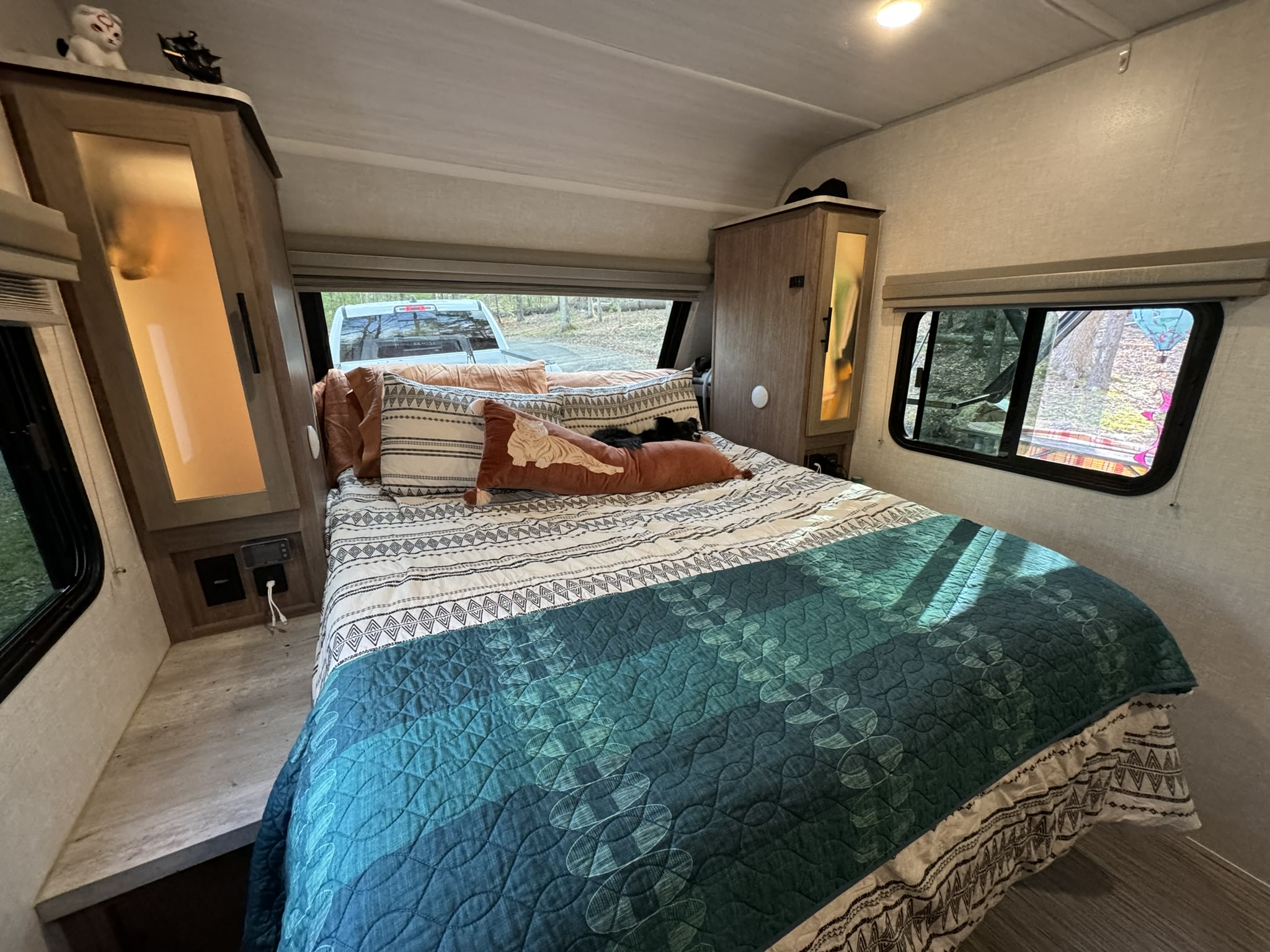 Cozy RV rental bedroom with a comfy bed, windows showing outside, and a small dog napping.. No Boundaries 19 2022