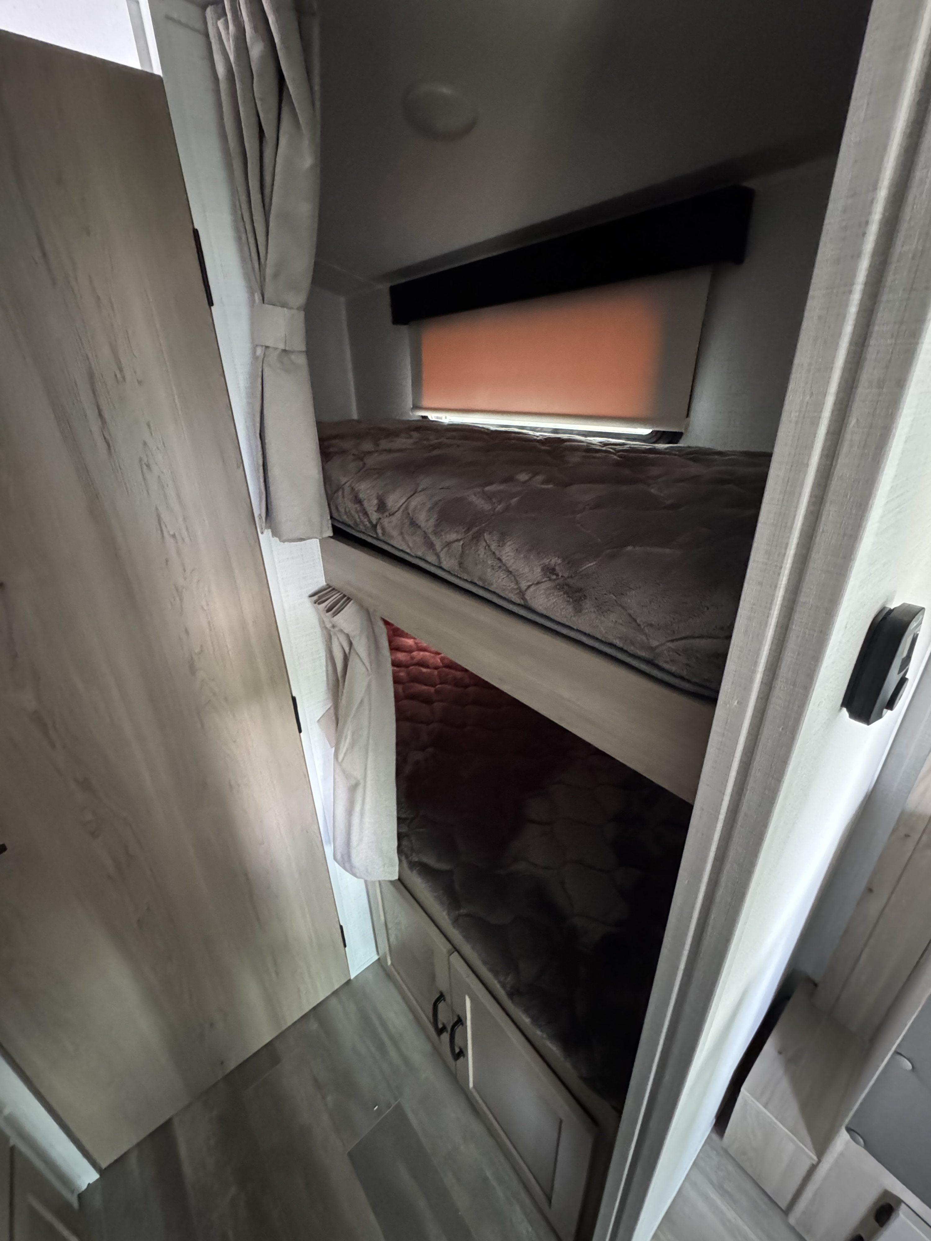 Cozy bunk beds in an RV rental, complete with soft bedding, window blinds, and storage cabinets. Perfect for family trips.. Forest River Flagstaff E-Pro 20BHS 2025