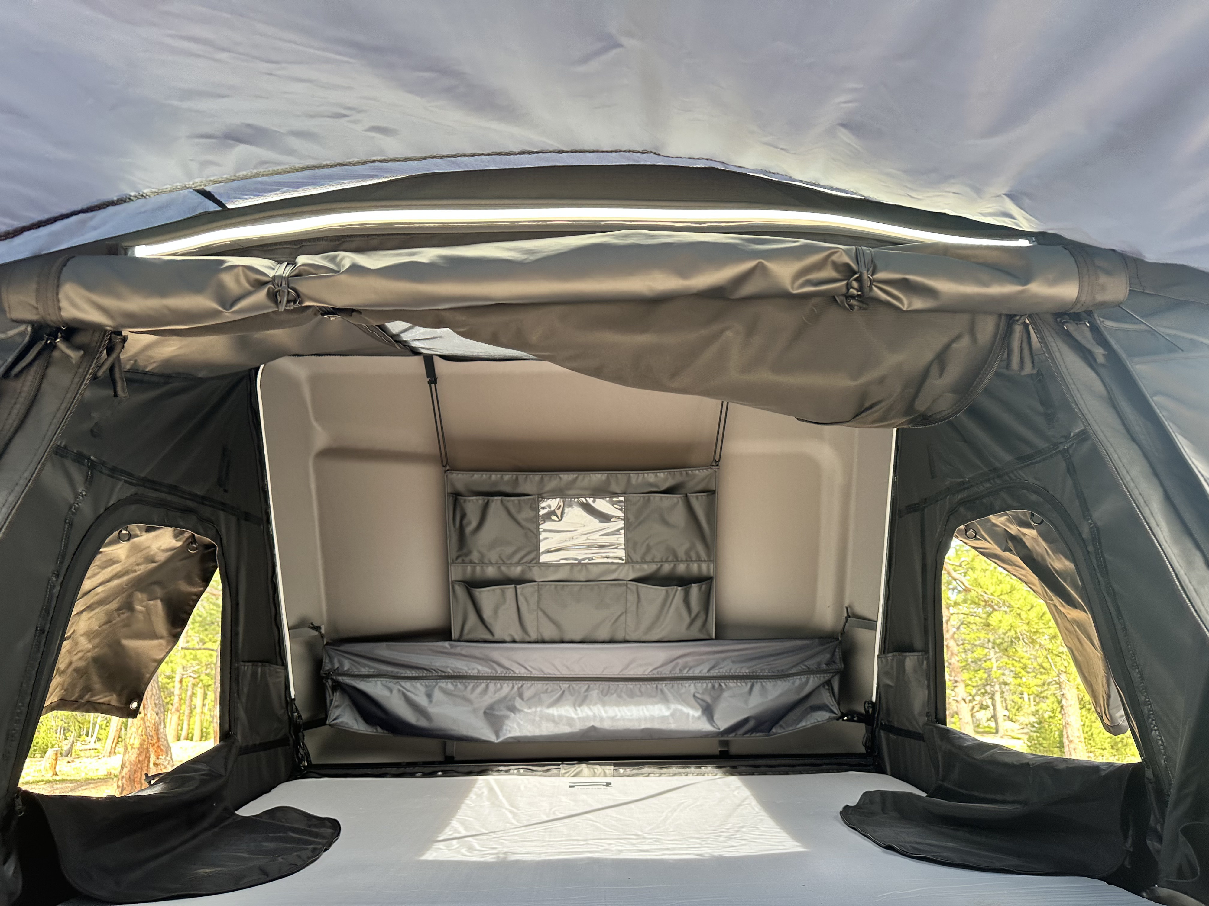 Inside an RV rental: a comfy tent sleeping area with bright LED lighting, wall storage, and scenic forest views for camping.. 3TMCZ5AN8MM421865 Toyota 2021