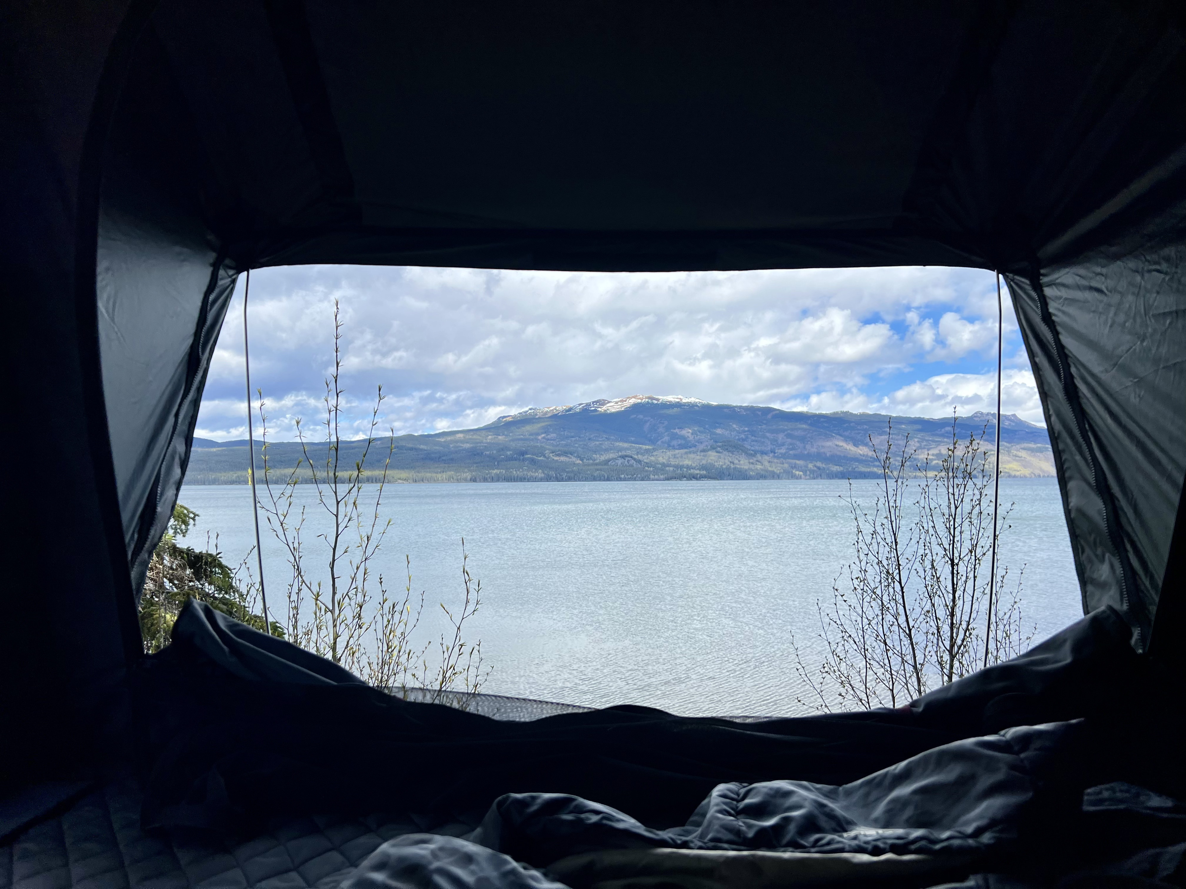 Wake up to this! Inside an RV rental, a stunning view of a calm lake, mountains, and budding trees awaits.. Toyota Tacoma 2020