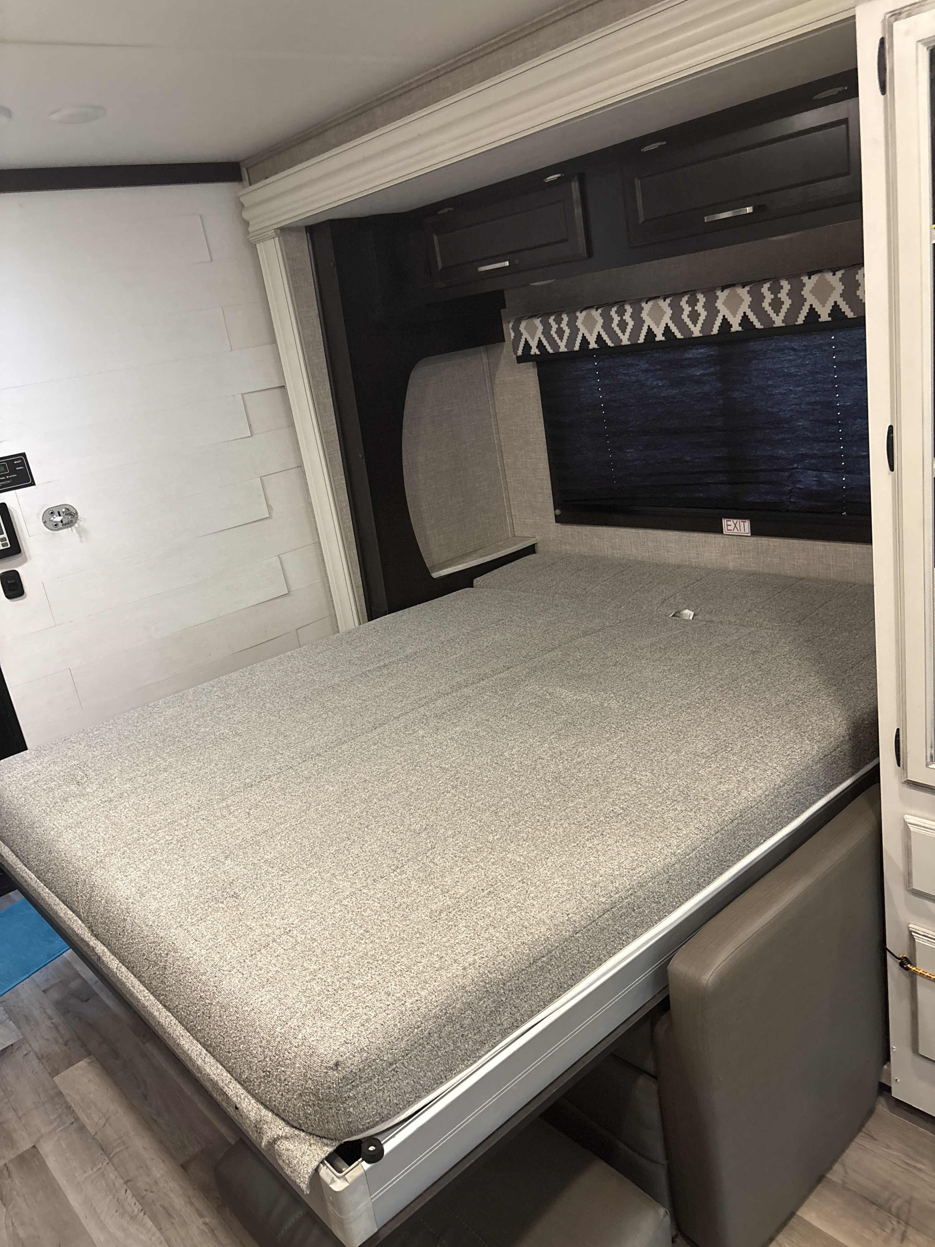 RV rental: Full view of a grey murphy bed extended, revealing compact living space with cabinetry and wall controls.. Jayco Redhawk 2022