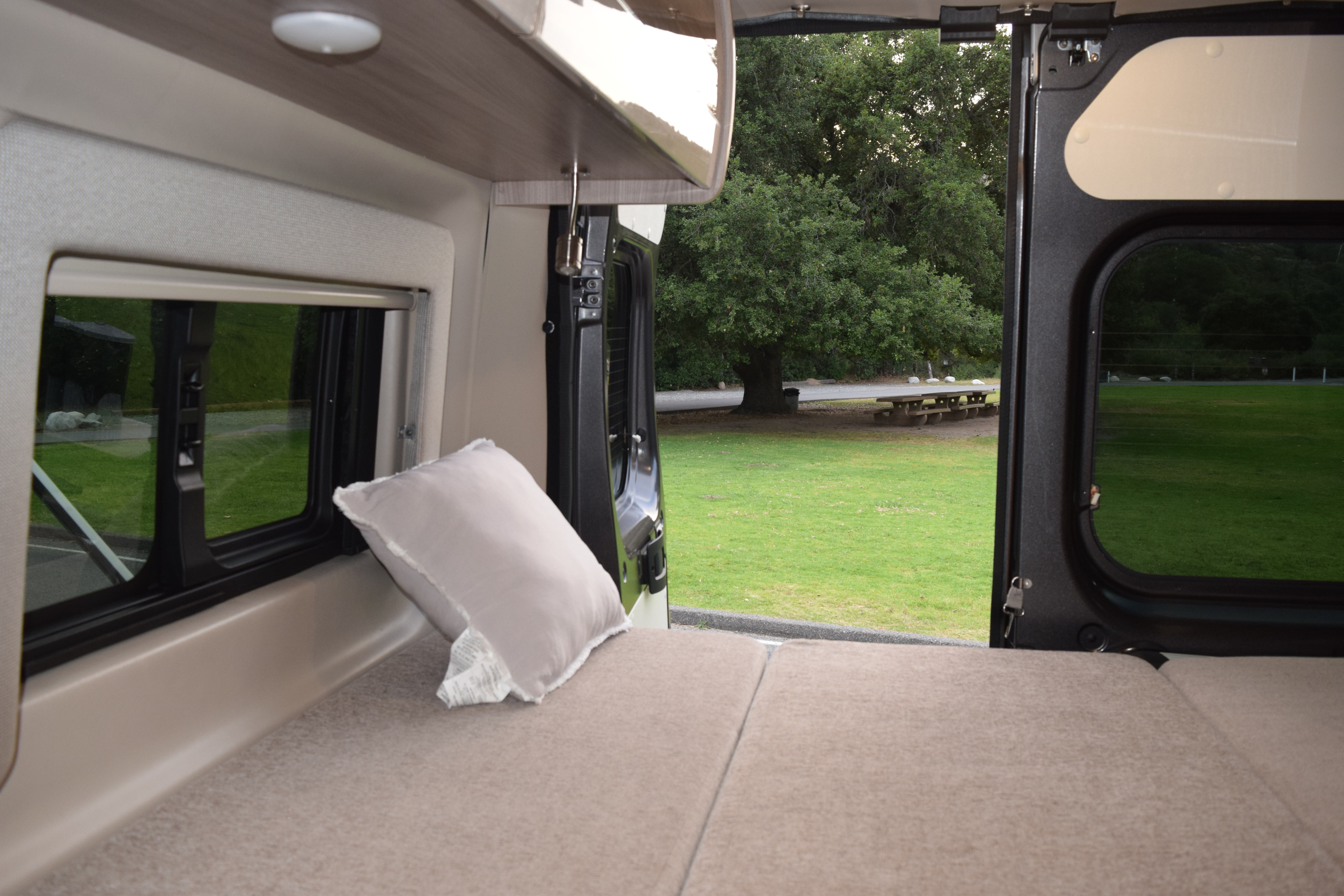 Experience RV rental comfort: cozy bed inside, scenic park view with a large tree & picnic table right outside.. Thor Sequnce 2023