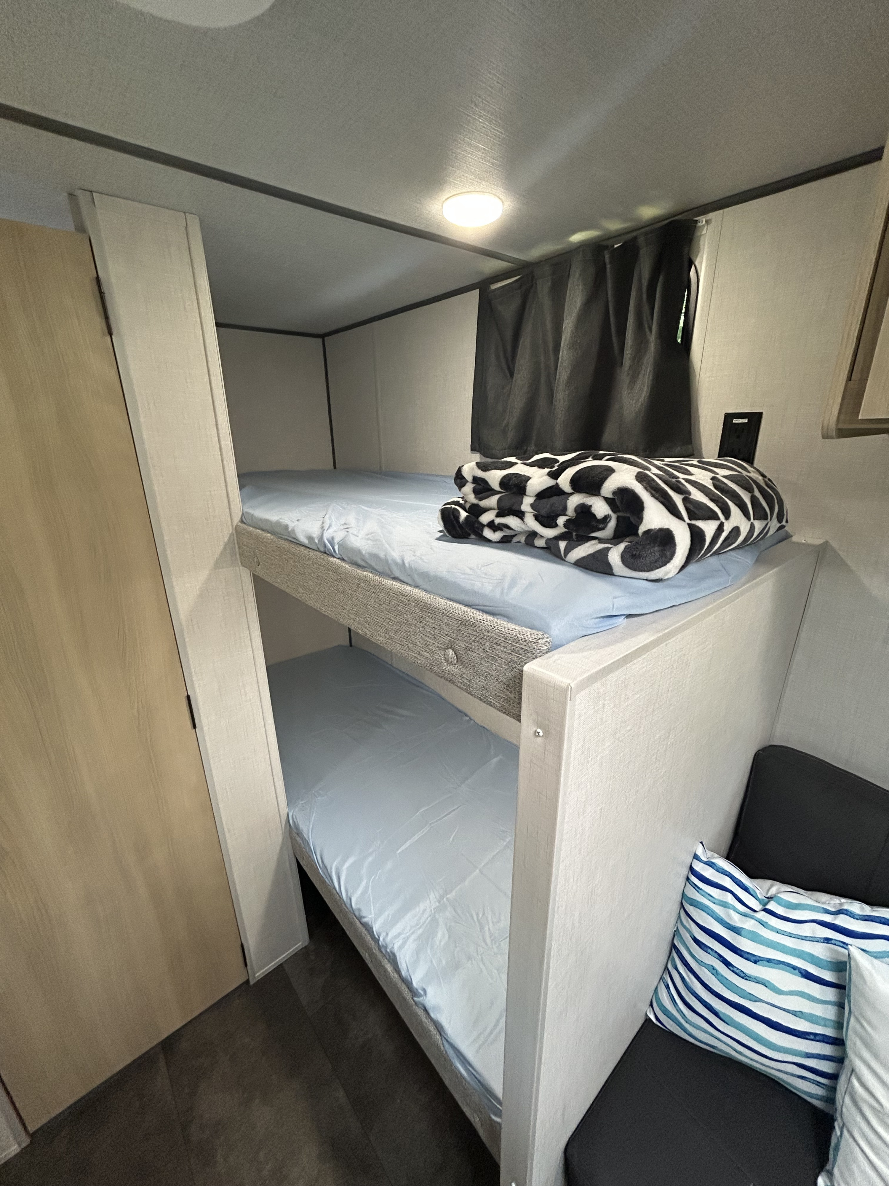 RV rental bunk beds: A compact interior with comfortable bunk beds, light blue sheets, and a cozy blanket, perfect for your next family adventure.. Forest River Salem FSX 14BHLE 2025