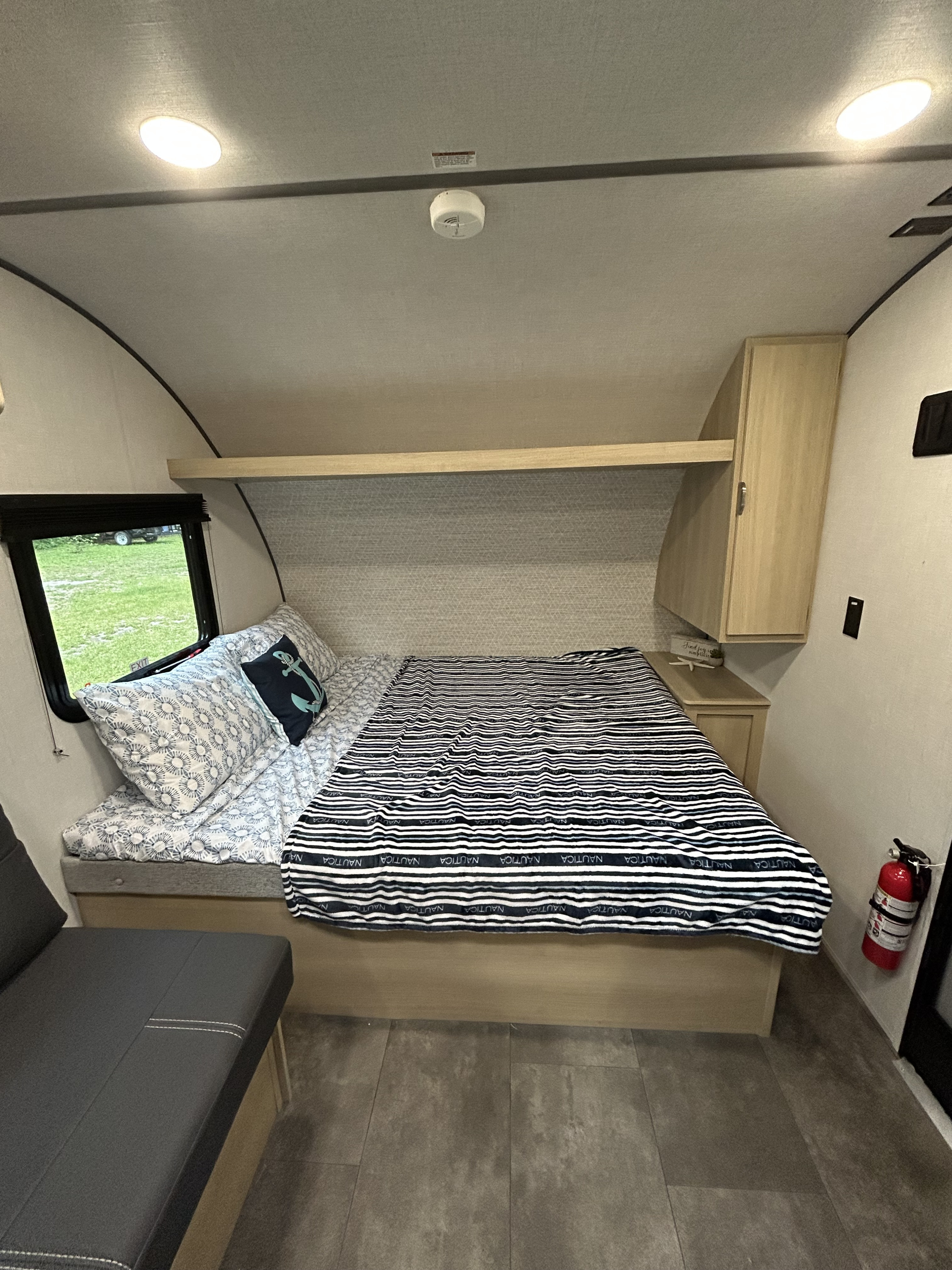 Cozy RV rental bedroom with nautical decor, comfortable bed, window views, and safety features like a fire extinguisher.. Forest River Salem FSX 14BHLE 2025