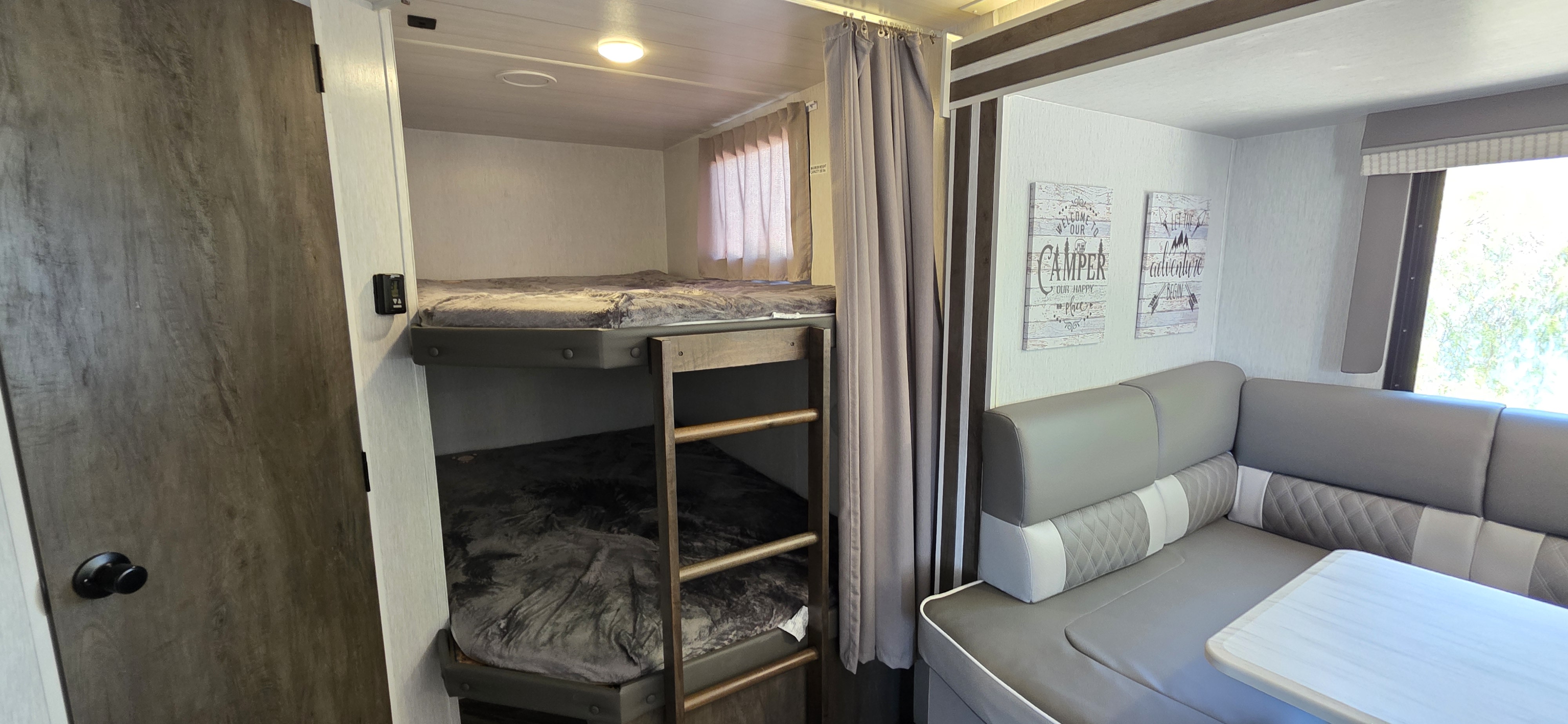 RV rental interior: cozy bunk beds on the left, a U-shaped dinette with decorative signs on the right, ready for your adventure.. Forest River Salem Cruise Lite 2022