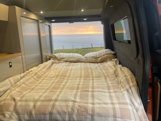 Experience stunning sunsets in your cozy RV rental! This campervan offers a comfortable bed with an epic ocean view for van life adventures.. Ford Camper Van 2021