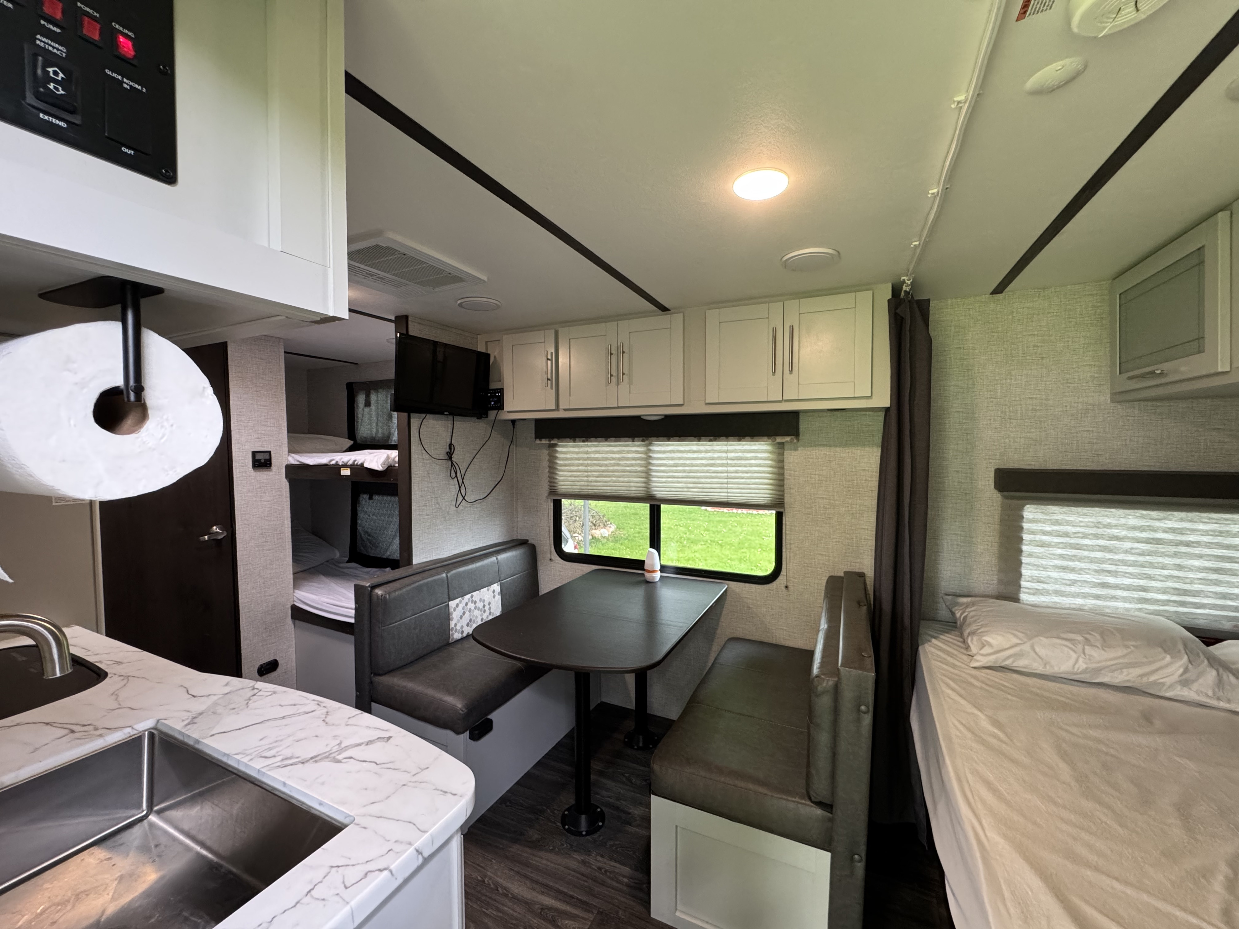 Modern RV rental interior featuring a kitchen, dinette with TV, bunk beds, and a comfortable main bed.. Keystone RV Bullet Crossfire 2021