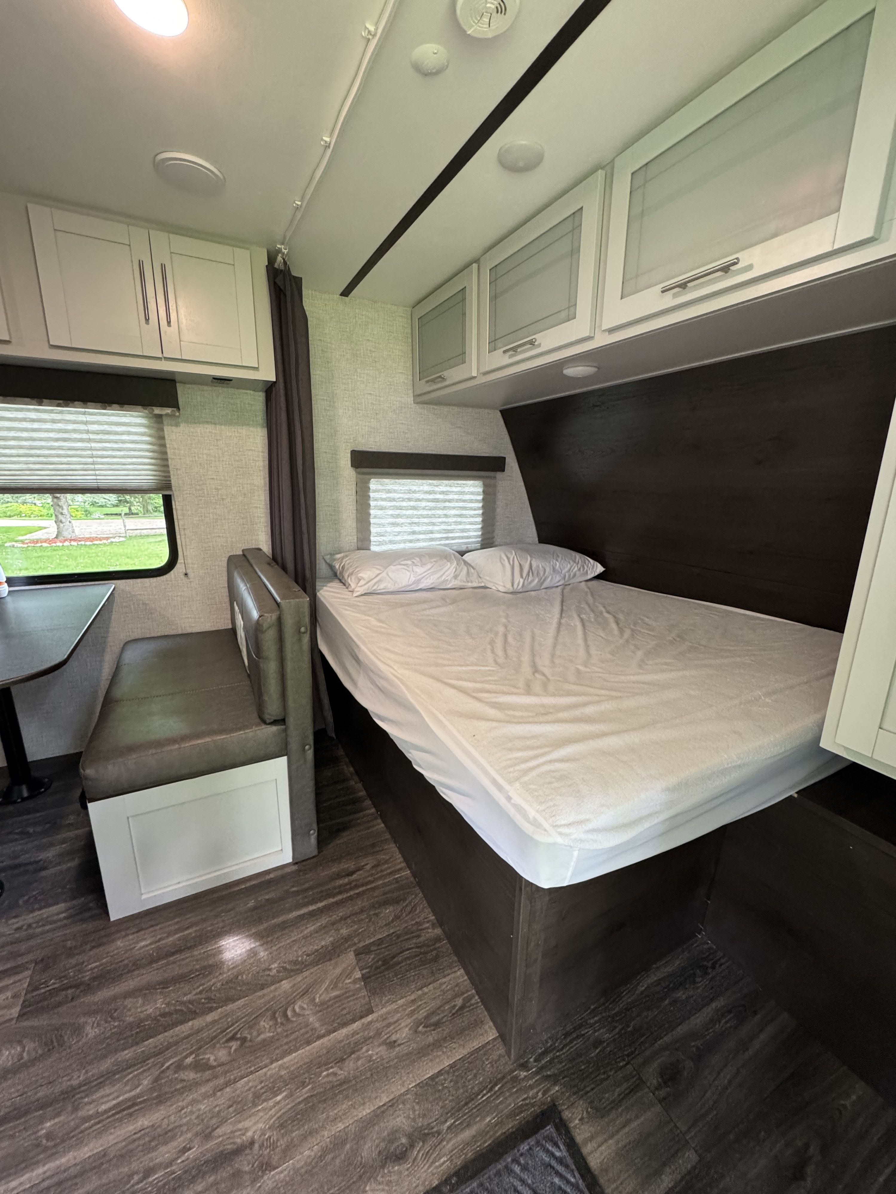 Cozy RV rental interior featuring a comfortable bed, dinette, and overhead storage for compact travel.. Keystone RV Bullet Crossfire 2021