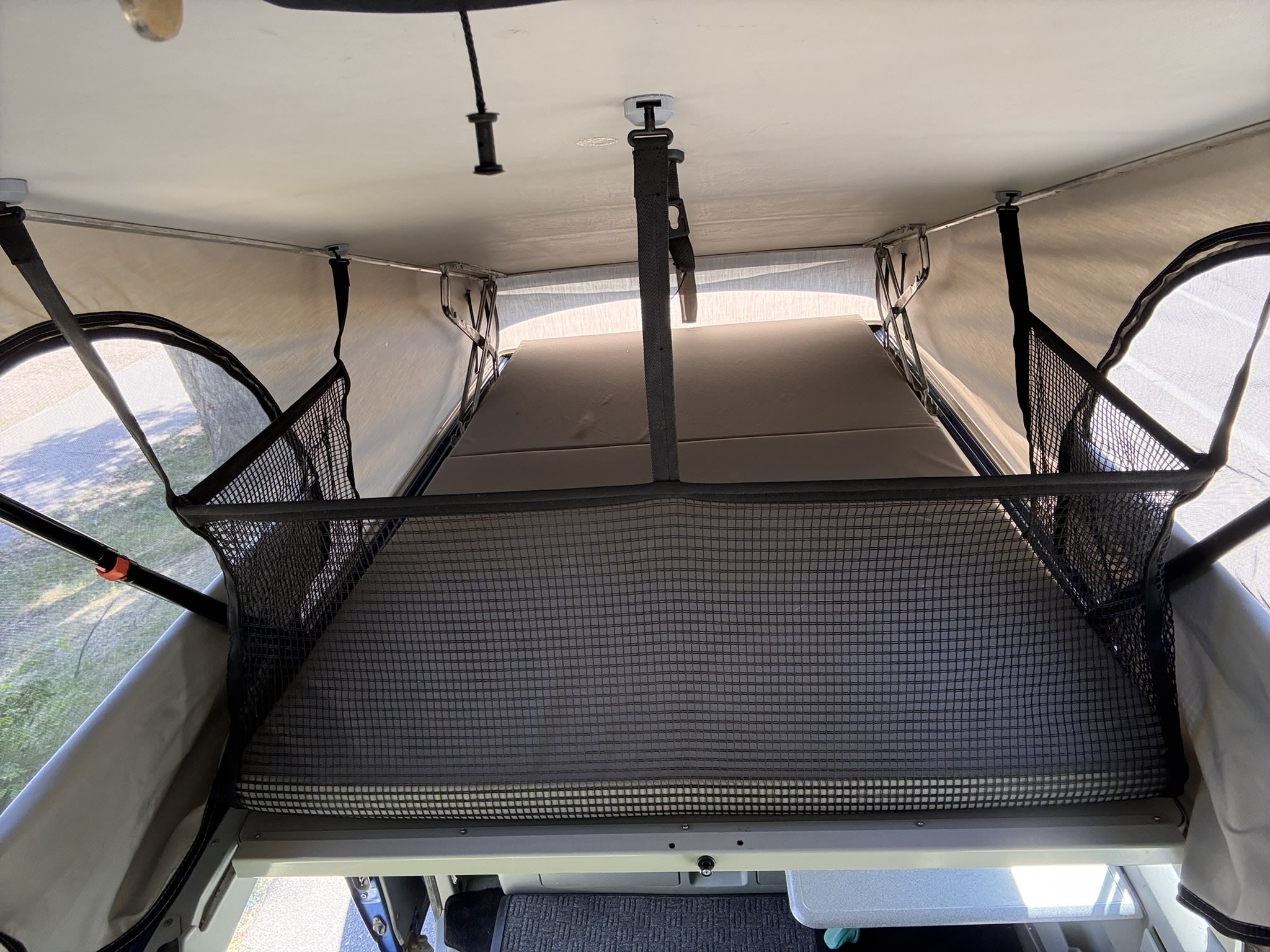 RV rental: Pop-top camper's upper sleeping area with mattress, net barrier, and canvas walls for adventure travel.. Volkswagen T4 Multivan Westfalia 2001