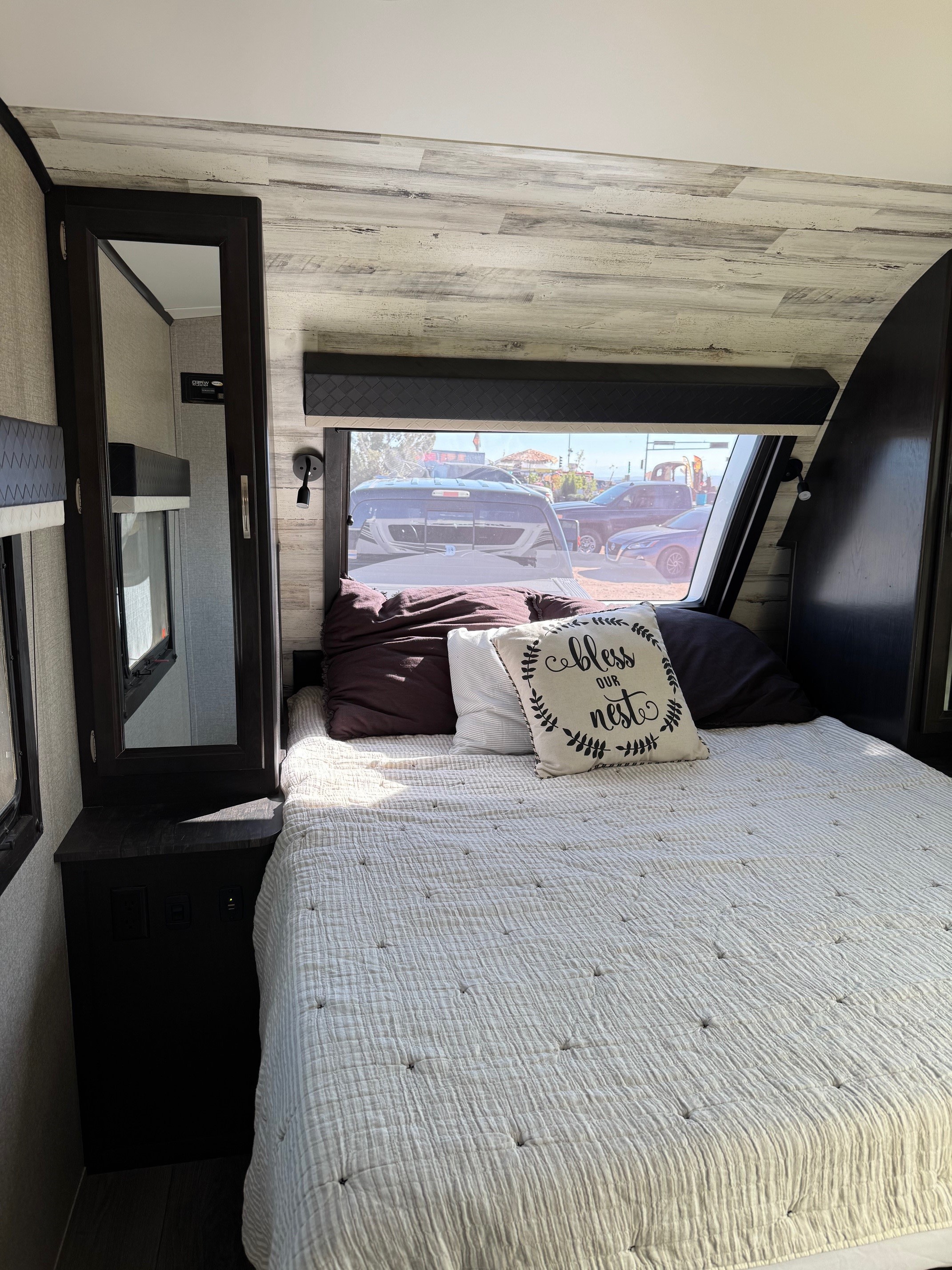 Cozy RV rental bedroom with a comfy bed, mirror, and window view, perfect for your travels.. Jayco White Hawk 2021