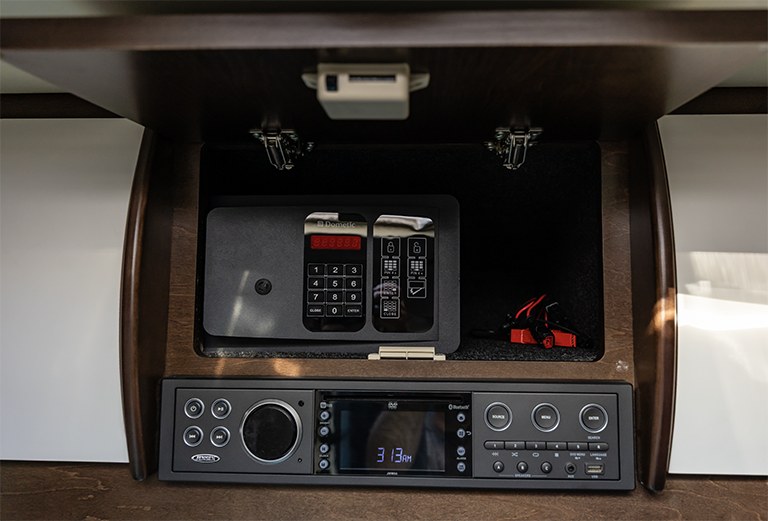 Inside this RV rental: a Dometic safe secures valuables in an open cabinet, with a Jensen entertainment system below.. Leisure Travel Vans Unity 2016