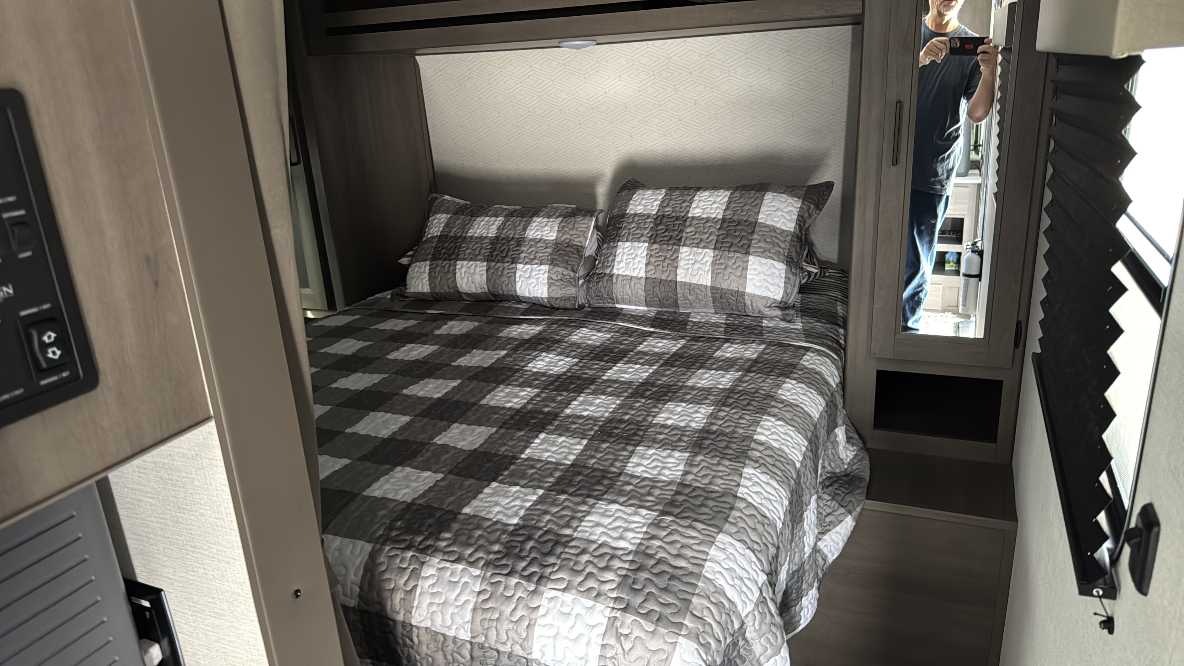 RV rental bedroom showcasing a cozy, checkered bed. Features include overhead storage and a mirrored cabinet.. Grand Design 26BHX 2025