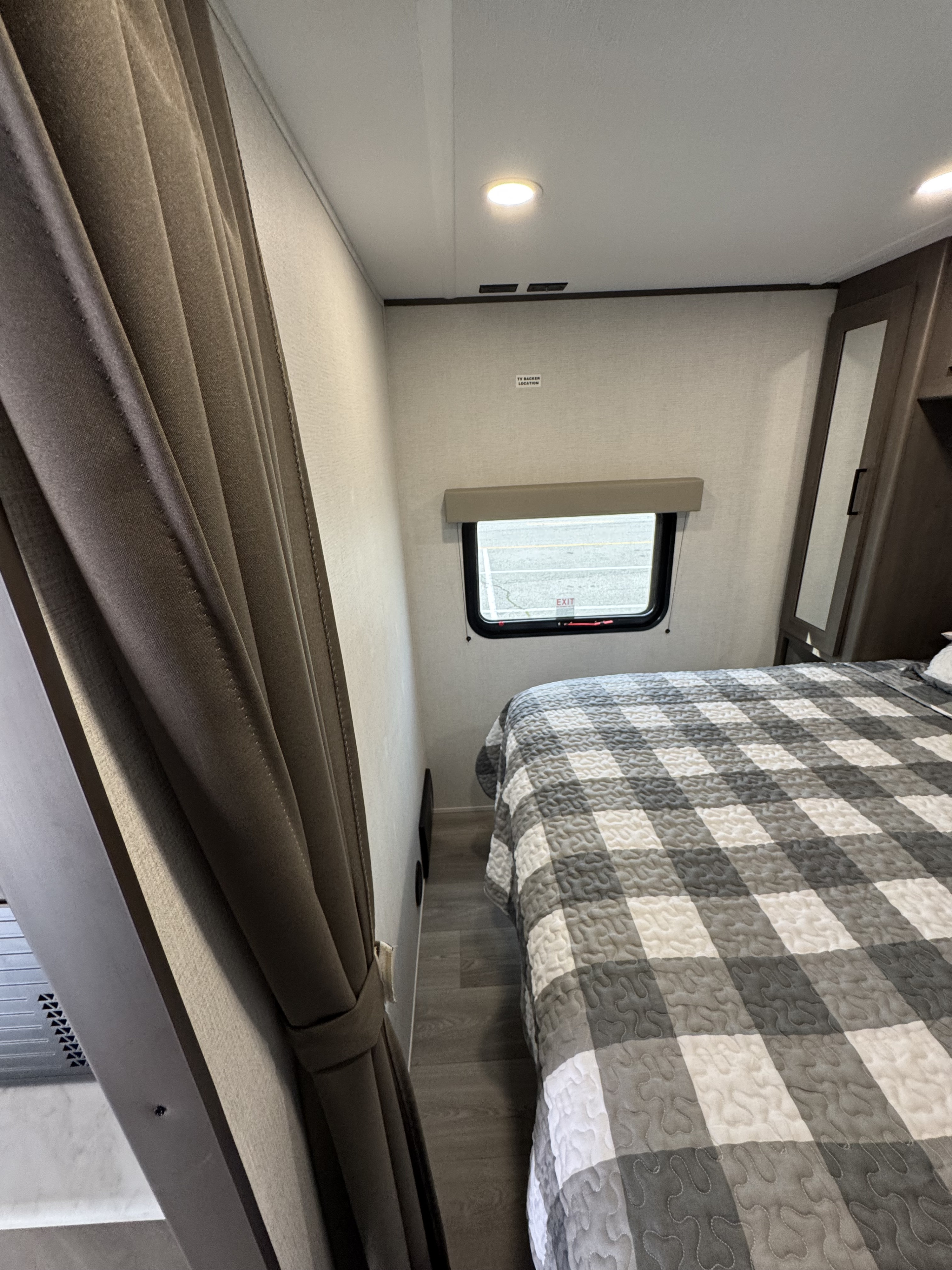 Comfortable RV rental bedroom featuring a checkered bed, window, and built-in wardrobe for storage.. Grand Design 26BHX 2025