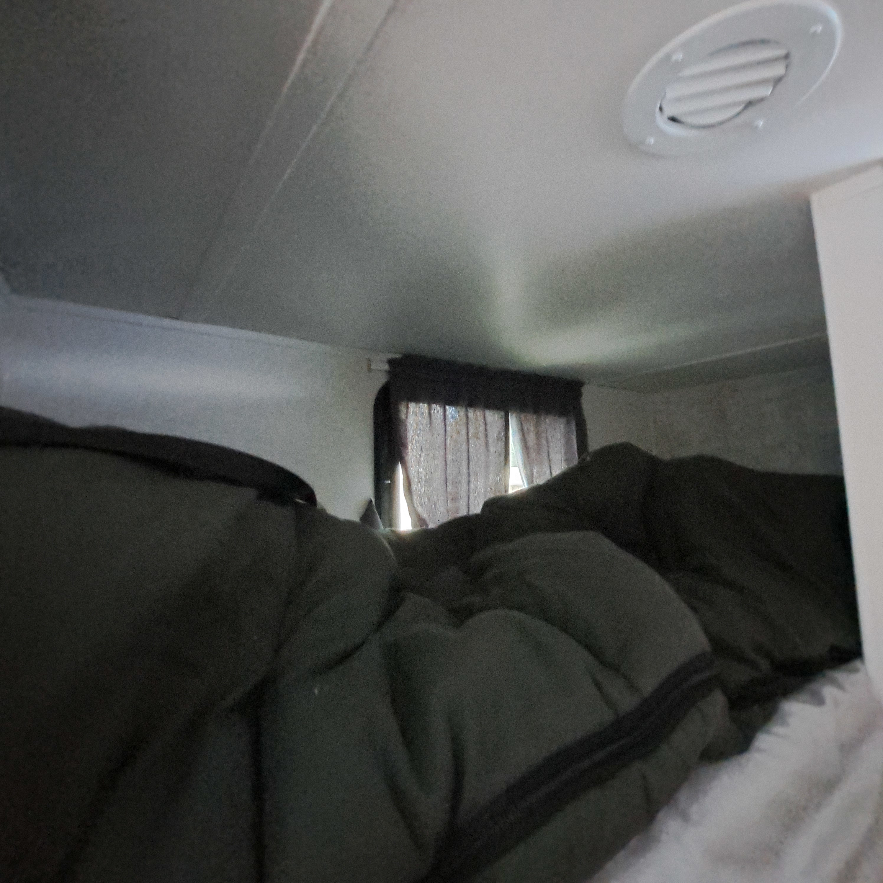 RV rental: Inside a cozy overhead bunk with dark green sleeping bags, a window with curtains, and a ceiling vent.. Winnebago Access 26BH 2025