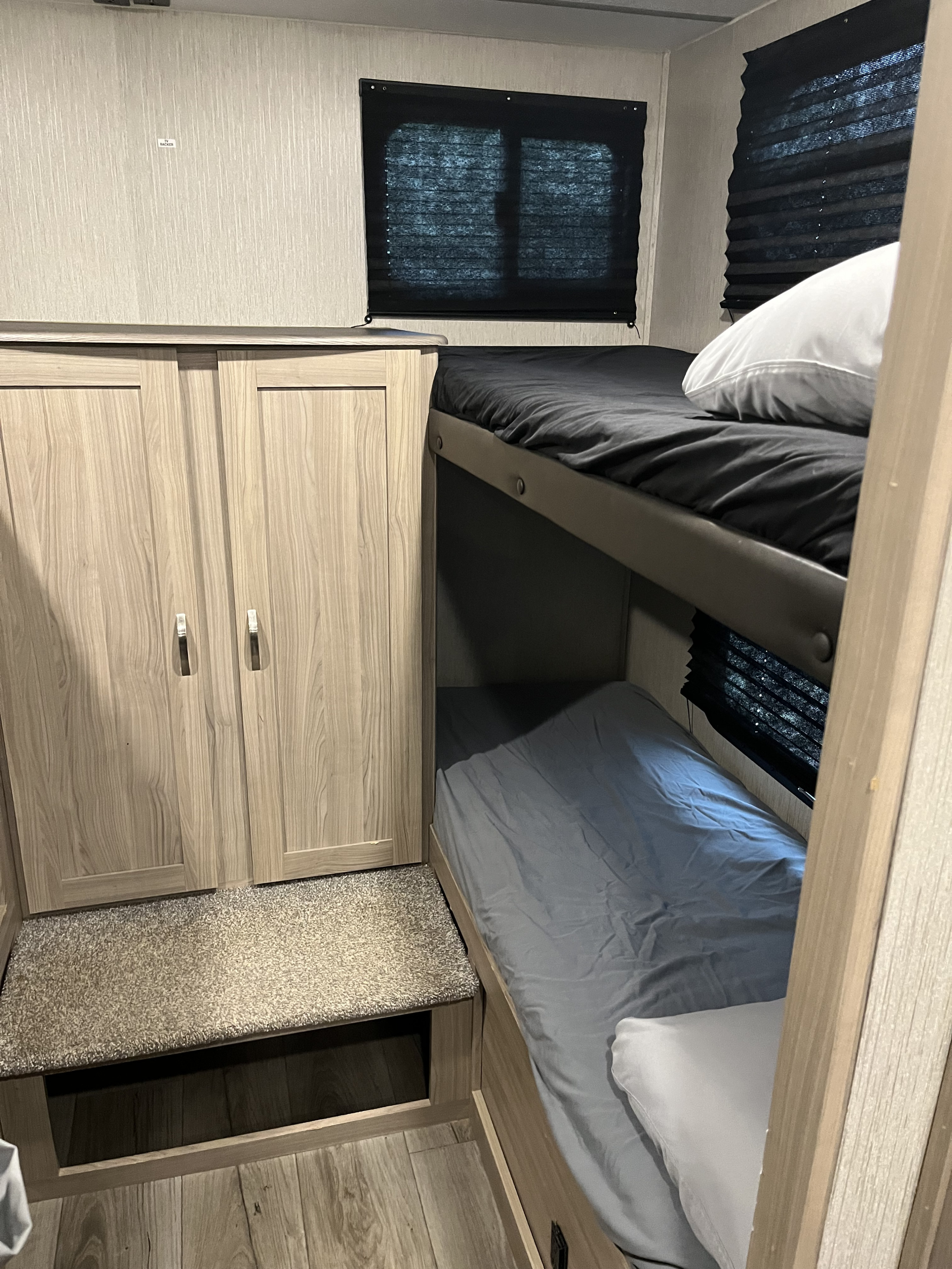 Cozy RV rental sleeping area featuring bunk beds with clean linens, a built-in wardrobe, and shaded windows.. Coachmen Freedom Express Ultra Lite 292BHDS 2021