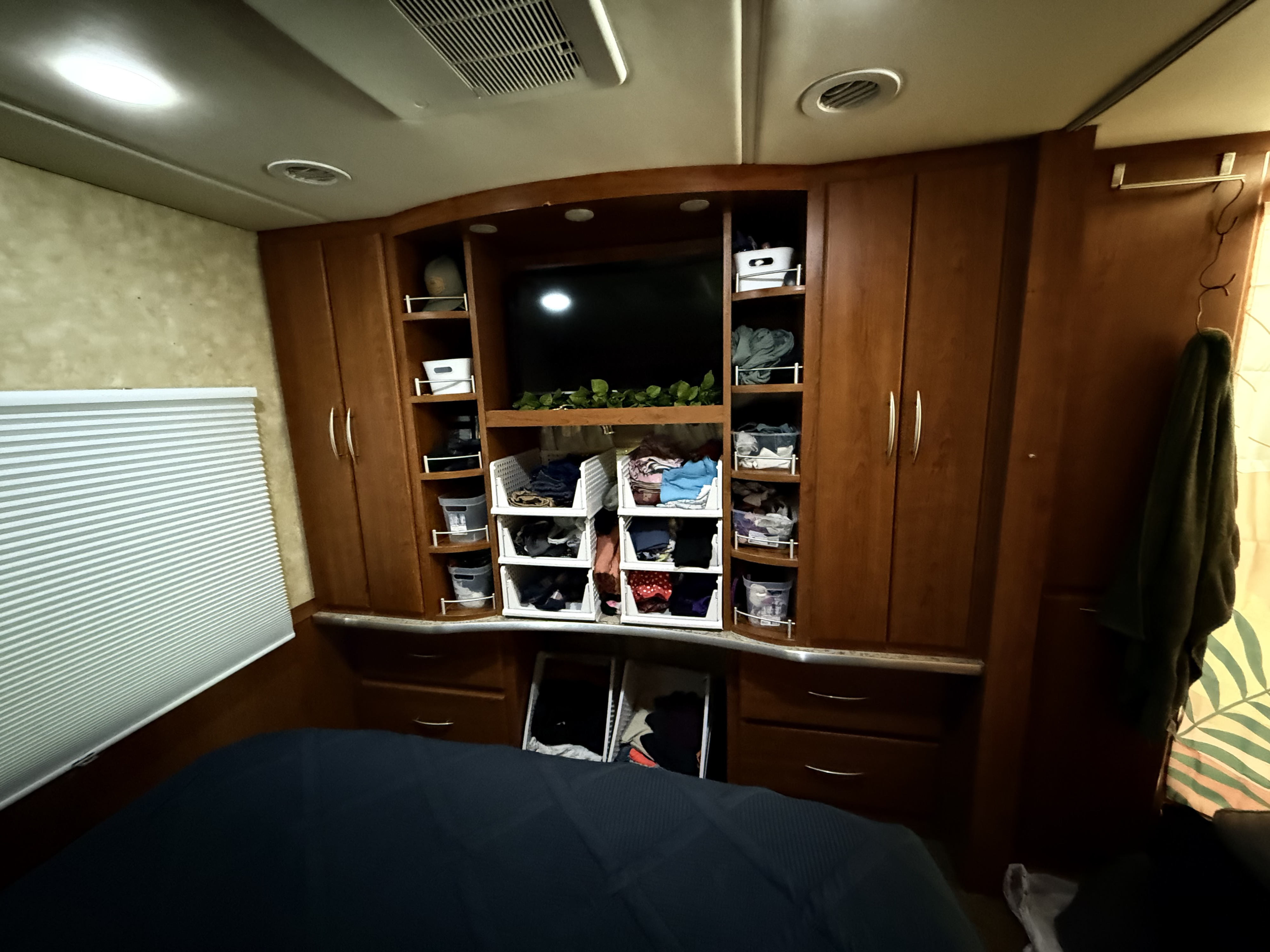 RV rental bedroom with efficient storage, showing a compact bed, TV, and organized shelving for comfortable travel.. Coachmen Mirada 2009