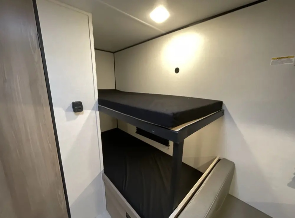 RV rental interior: cozy bunk beds with black mattresses & bright light. Perfect for travel accommodations.. Other Other 2025