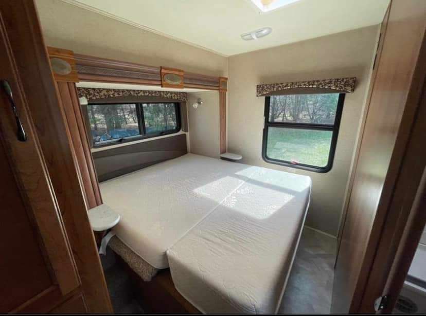 RV rental bedroom: spacious interior with an extendable bed, windows offering natural light, and storage.. Jayco Redhawk 2016