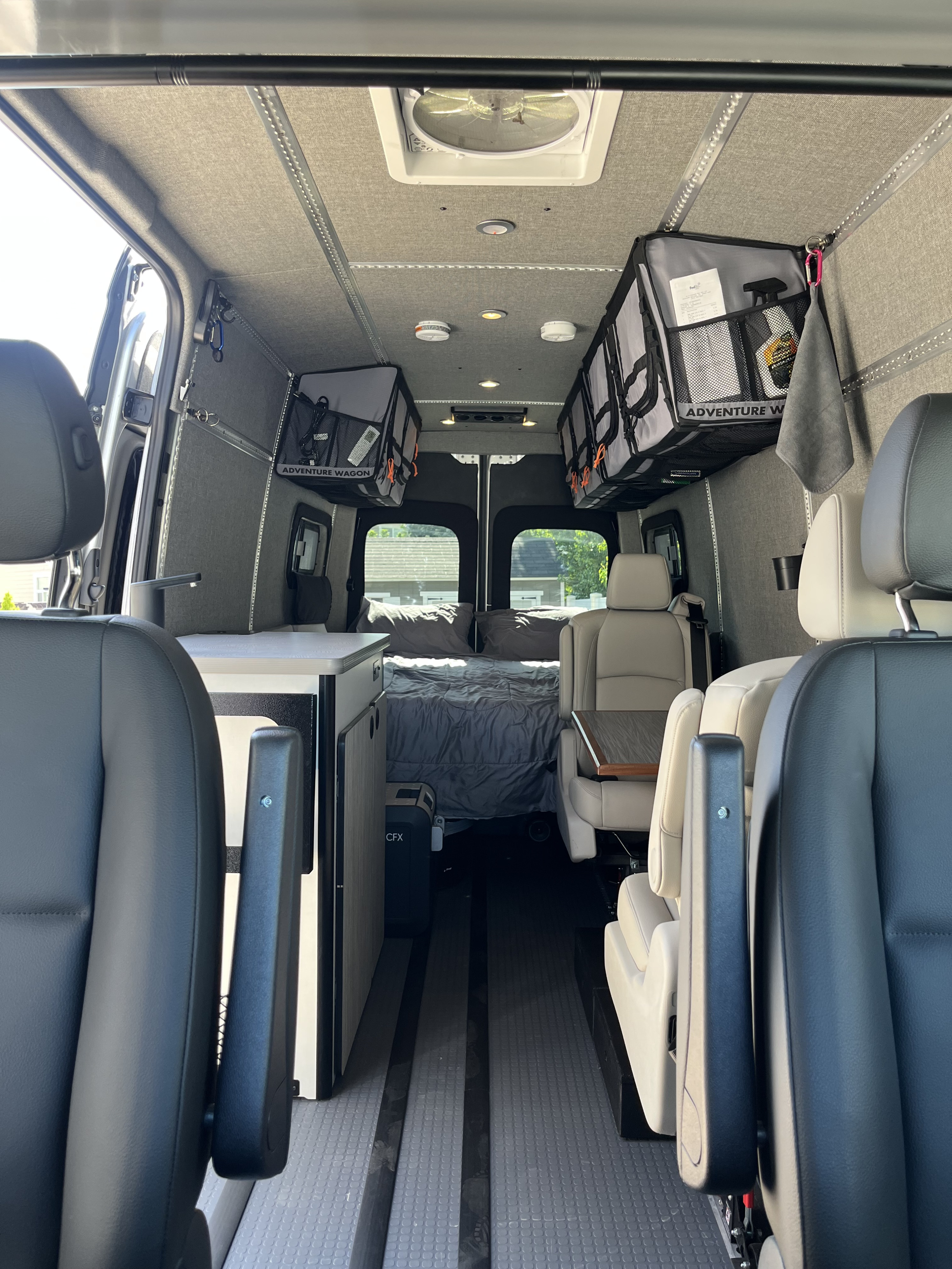 Spacious RV rental interior featuring flexible seating, kitchenette, bed, and ample overhead storage for mobile adventures.. Winnebago Adventure Wagon 2023