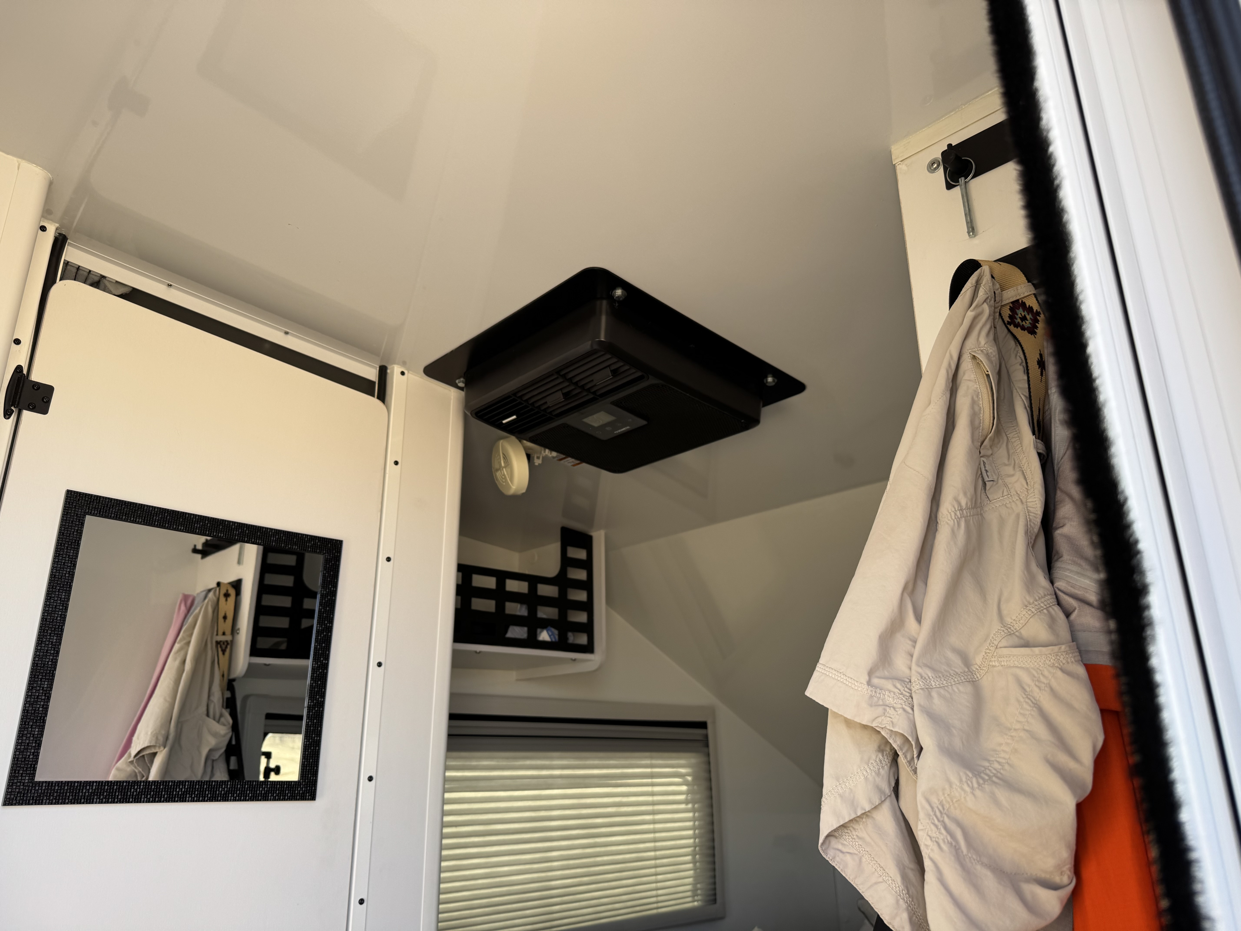 Compact RV rental interior featuring a Dometic AC unit on the ceiling, a mirror on the door, and space for hanging items.. Lance Enduro 1200EK 2024