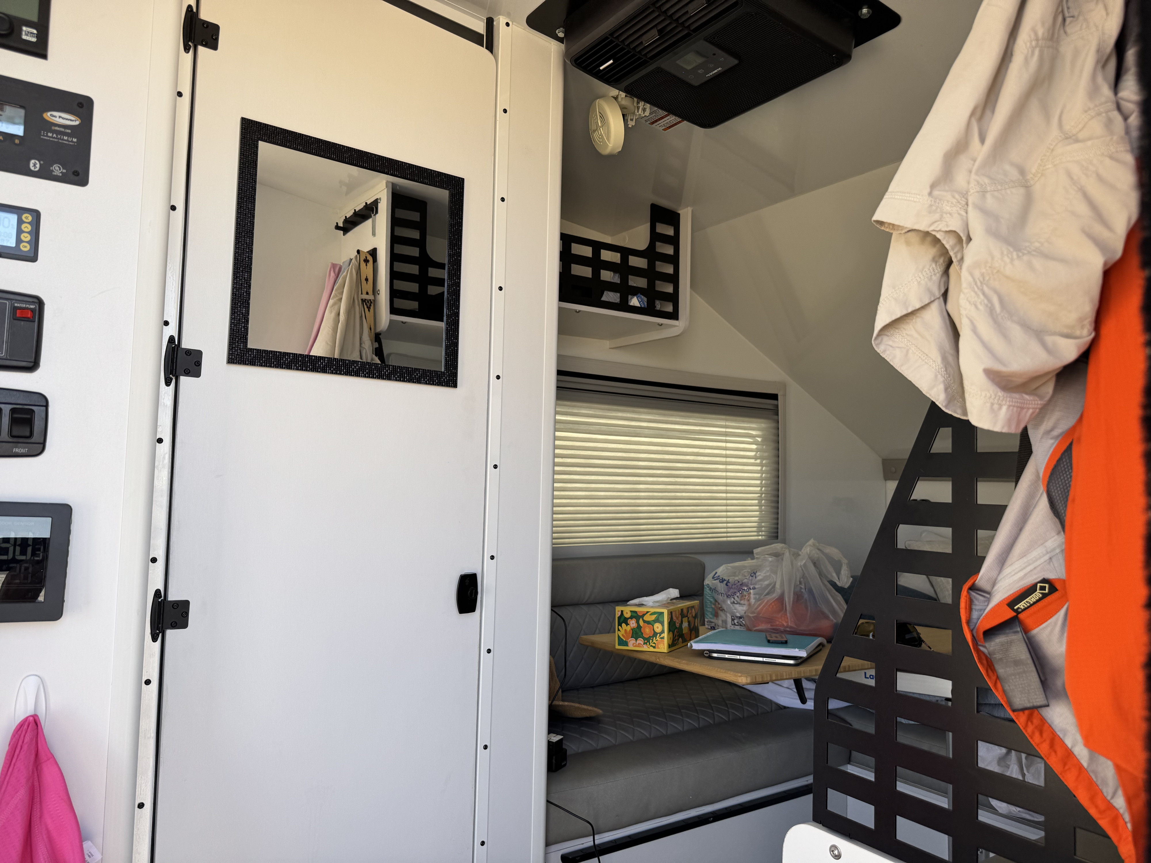 RV rental interior featuring control panels, mirrored door, bench seat, window with blinds, AC unit, and storage.. Lance Enduro 1200EK 2024