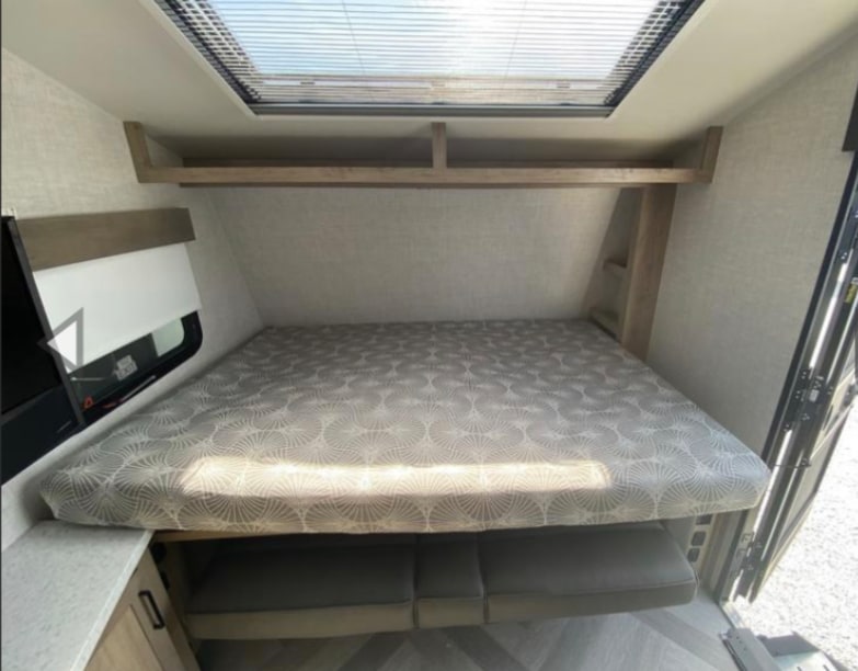 RV rental: Bright bedroom with a large bed, overhead shelf, and convertible seating below. Perfect for your next trip.. Ember Overland 2022