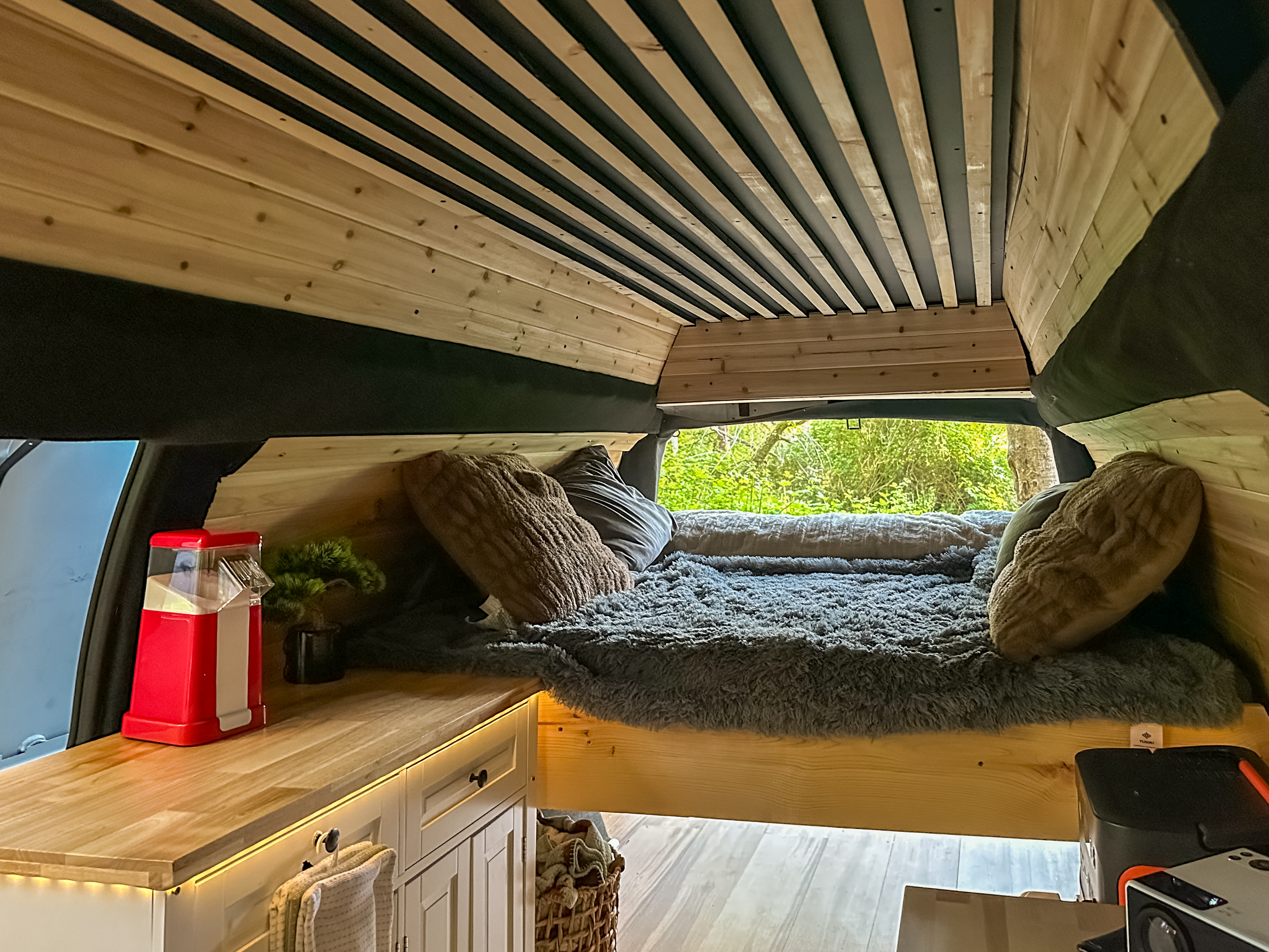 Cozy RV rental interior featuring a wood-paneled ceiling and walls, a comfortable bed, and a functional kitchen counter.. Chevrolet Express G3500 2007