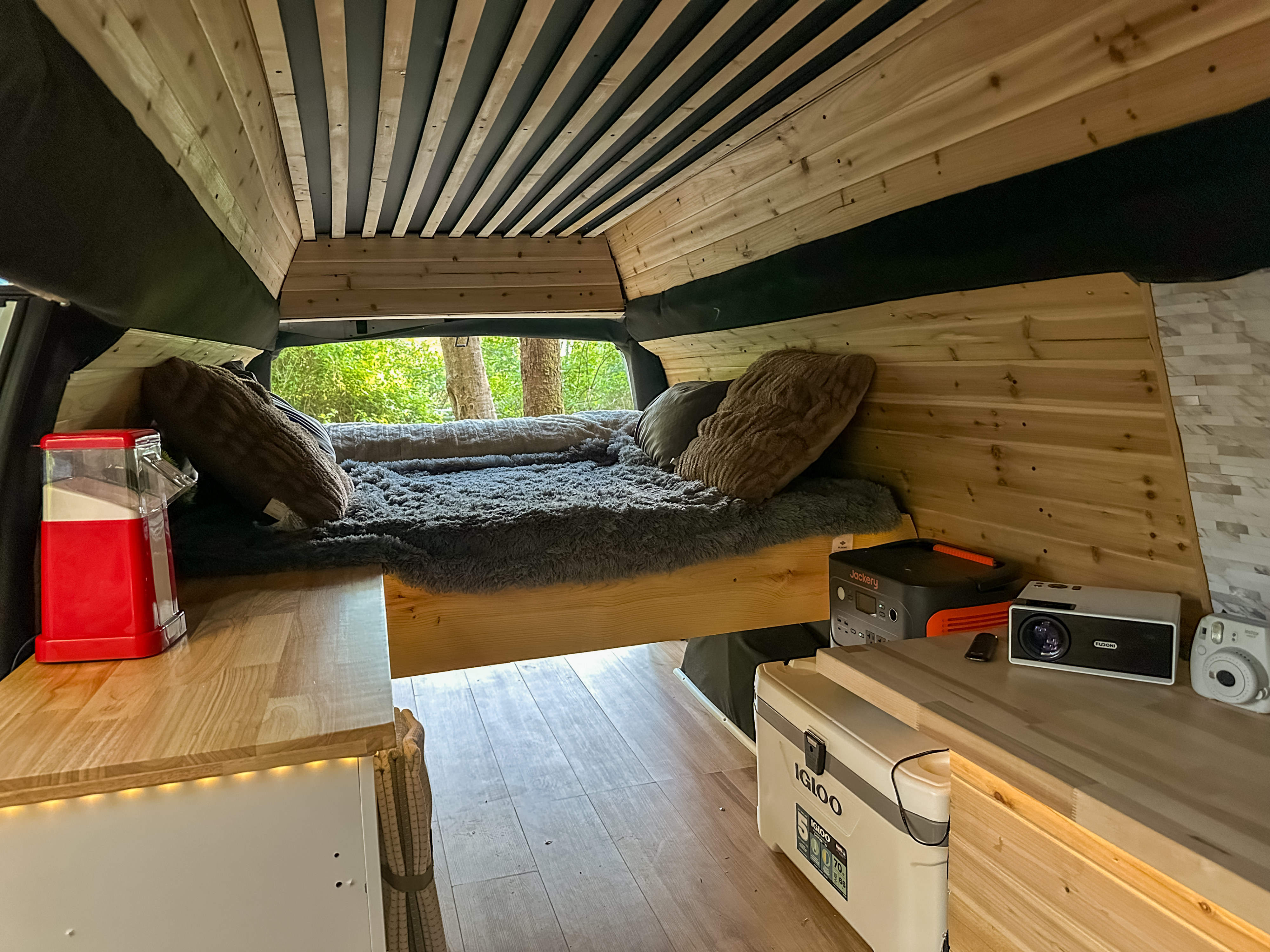 Cozy RV rental interior with wood details, bed, projector, and camera for your next road trip adventure.. Chevrolet Express G3500 2007